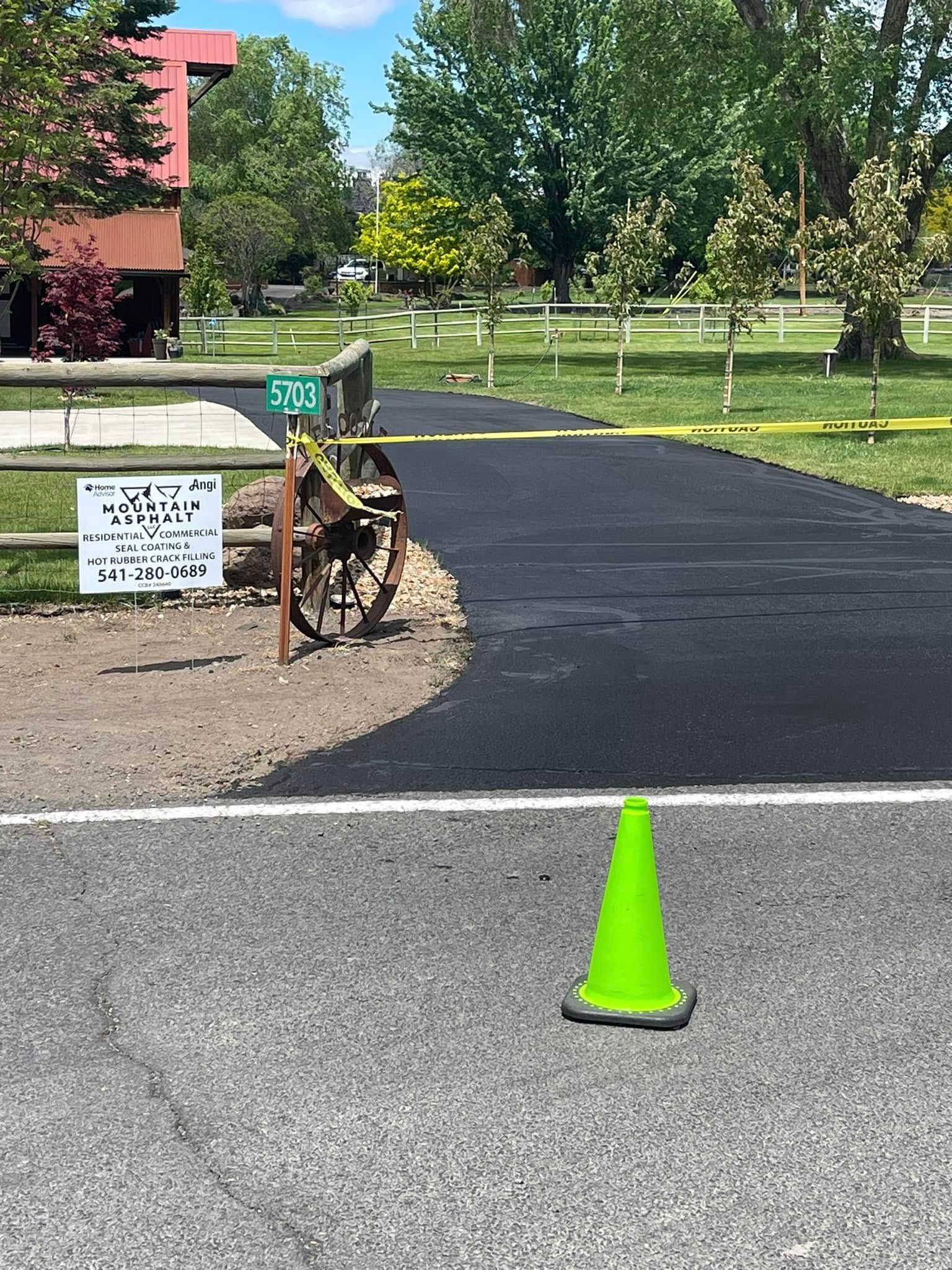 A green traffic cone is sitting on the side of a road.