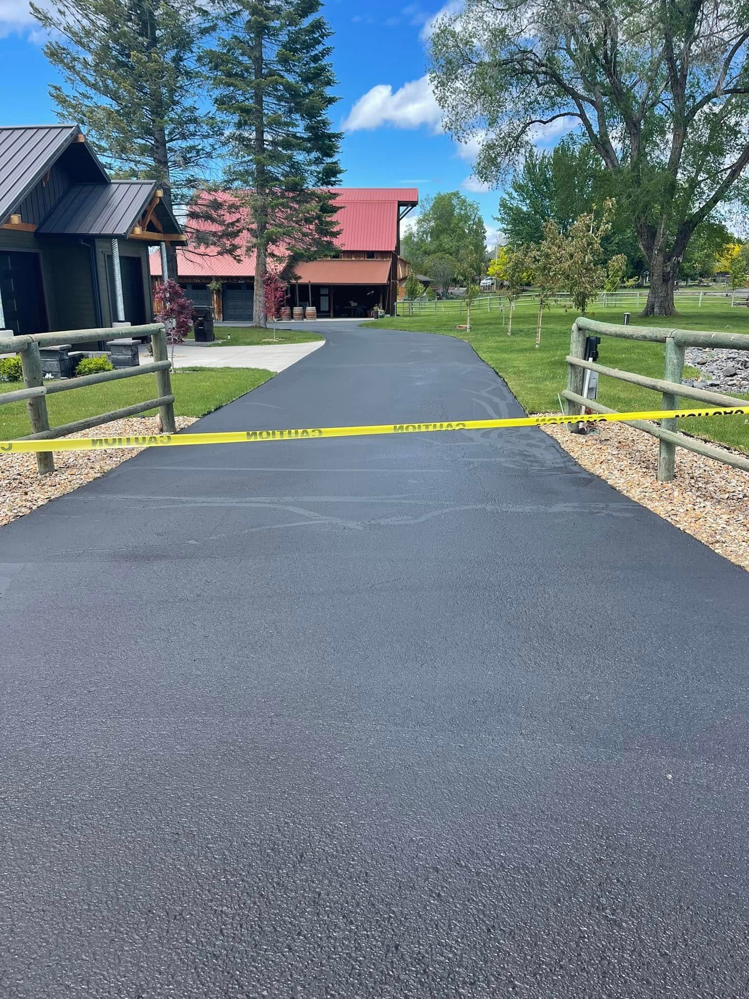 A driveway with a fence and a house in the background.