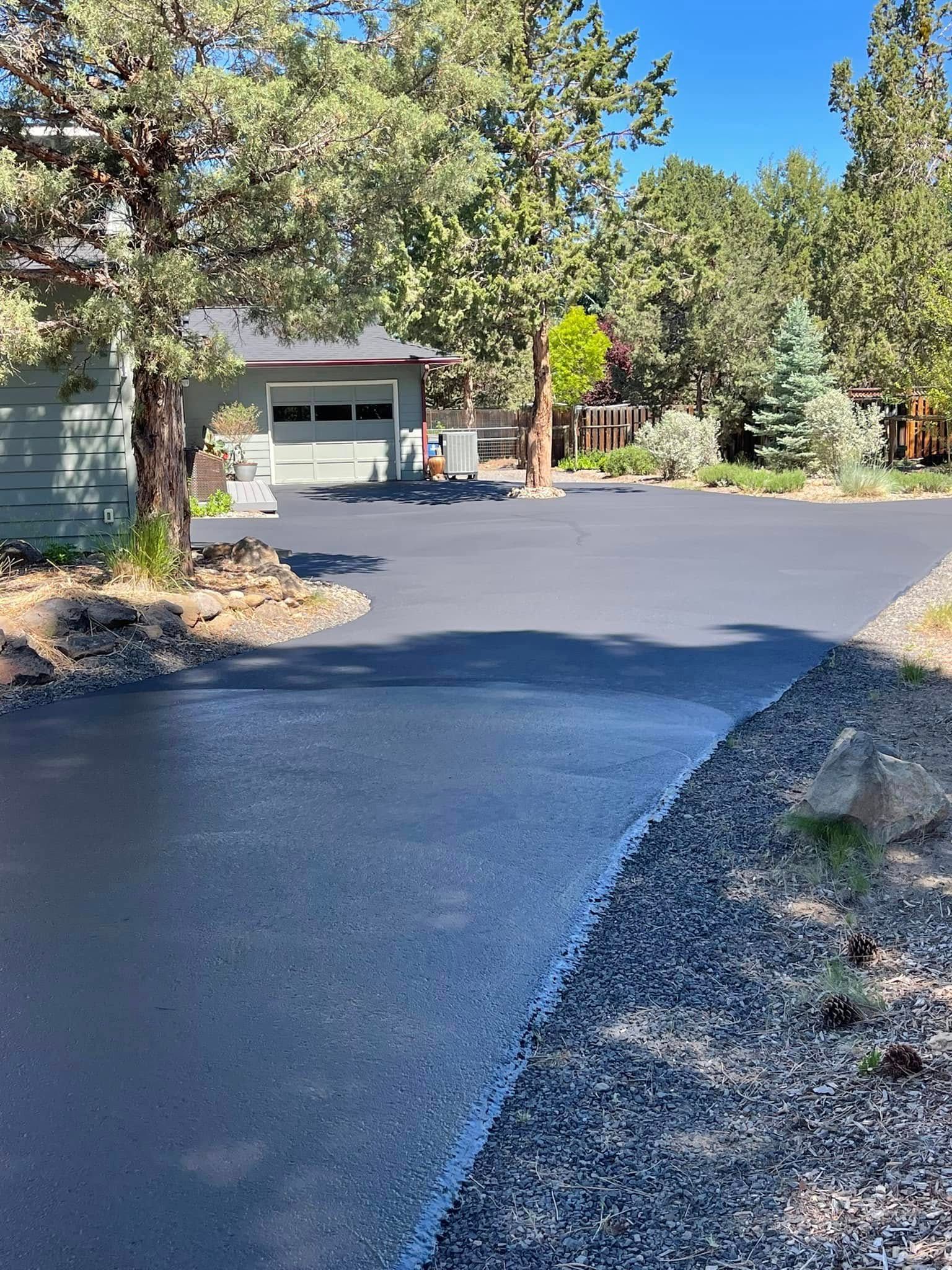 A driveway leading to a house with a garage and trees in the background.