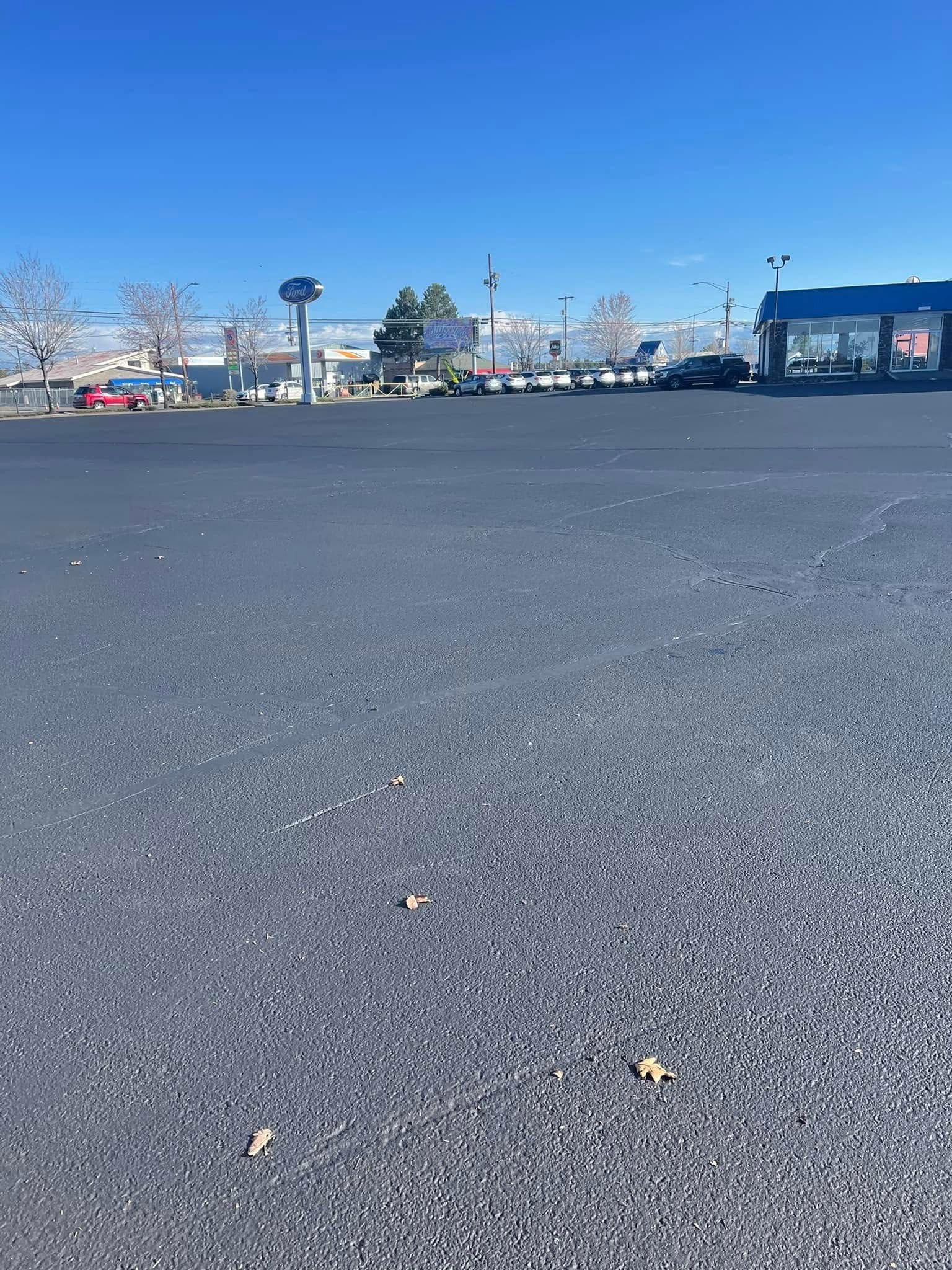 An empty parking lot with a building in the background on a sunny day.