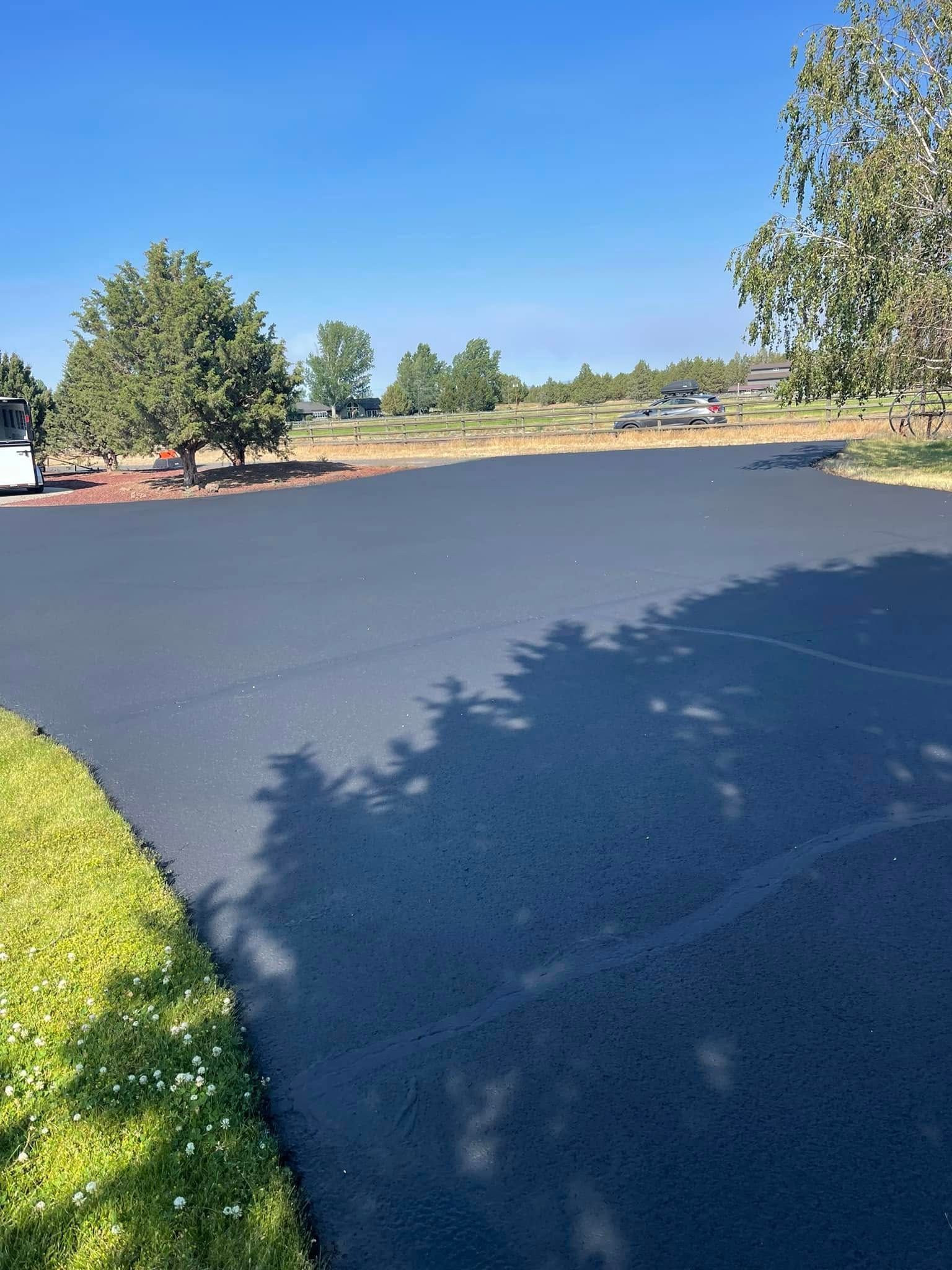 A shadow of a tree is cast on a newly paved driveway.