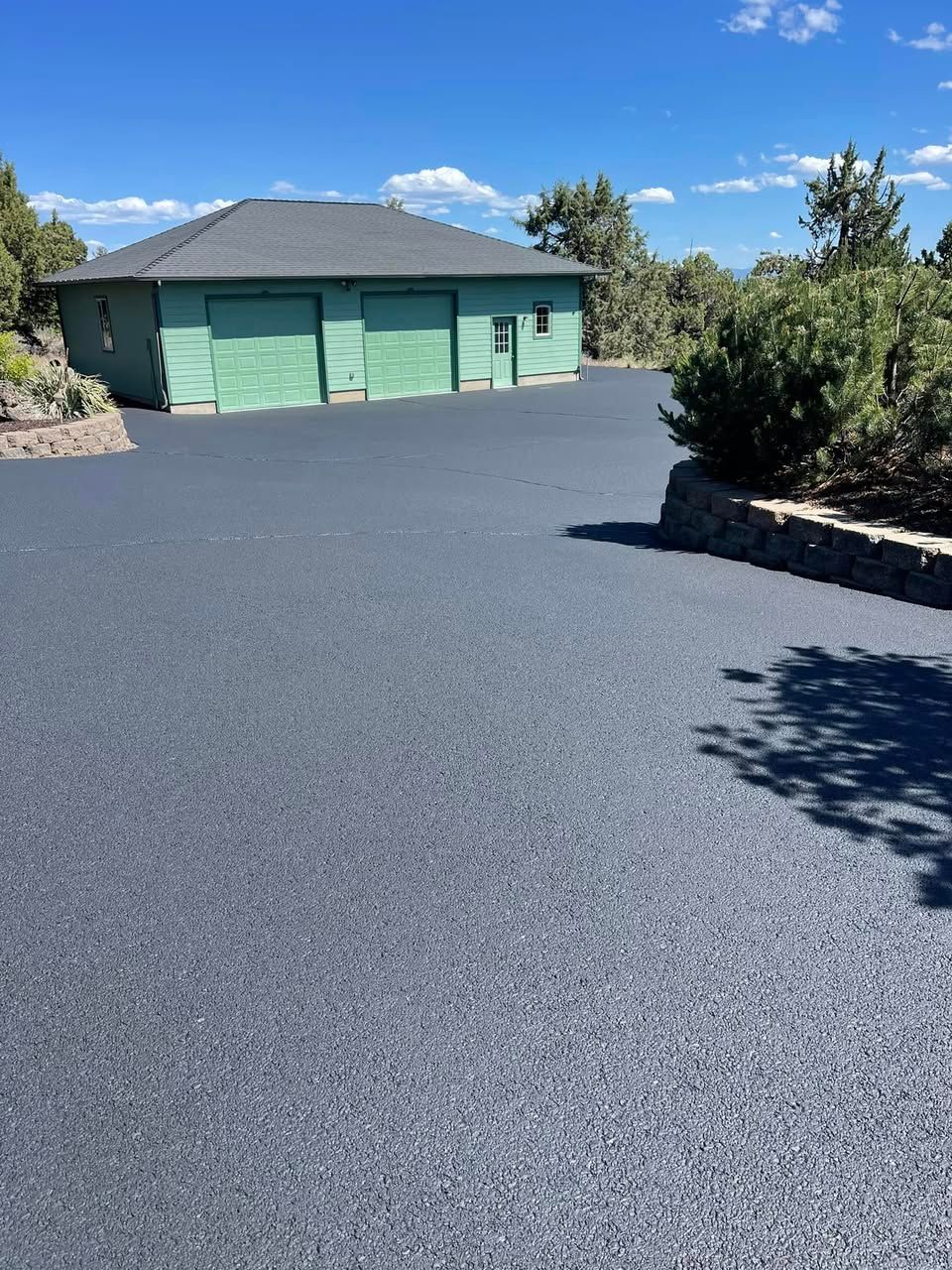 A green house is sitting in the middle of a driveway