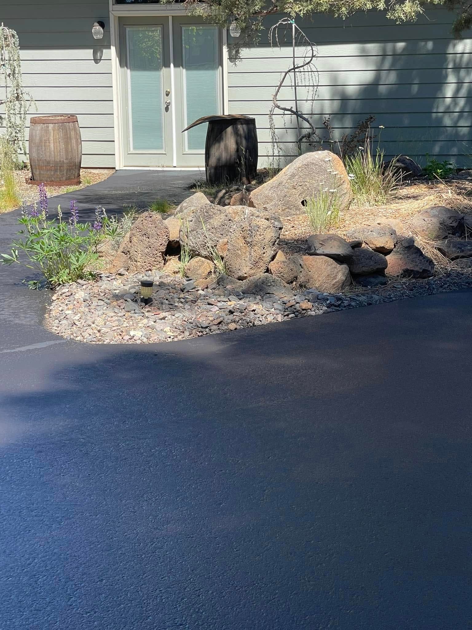 A house with a driveway and rocks in front of it.