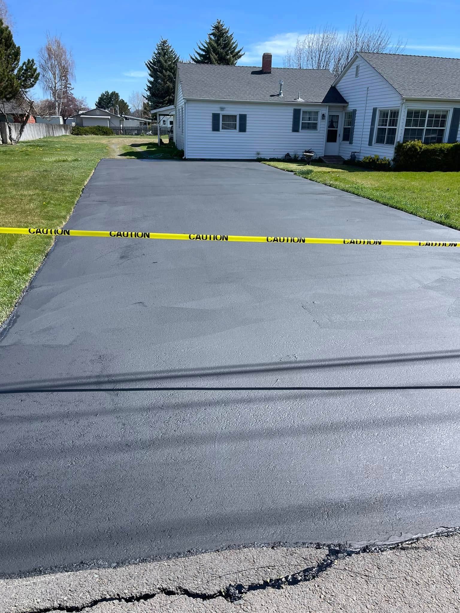 A driveway with a house in the background and a yellow tape.