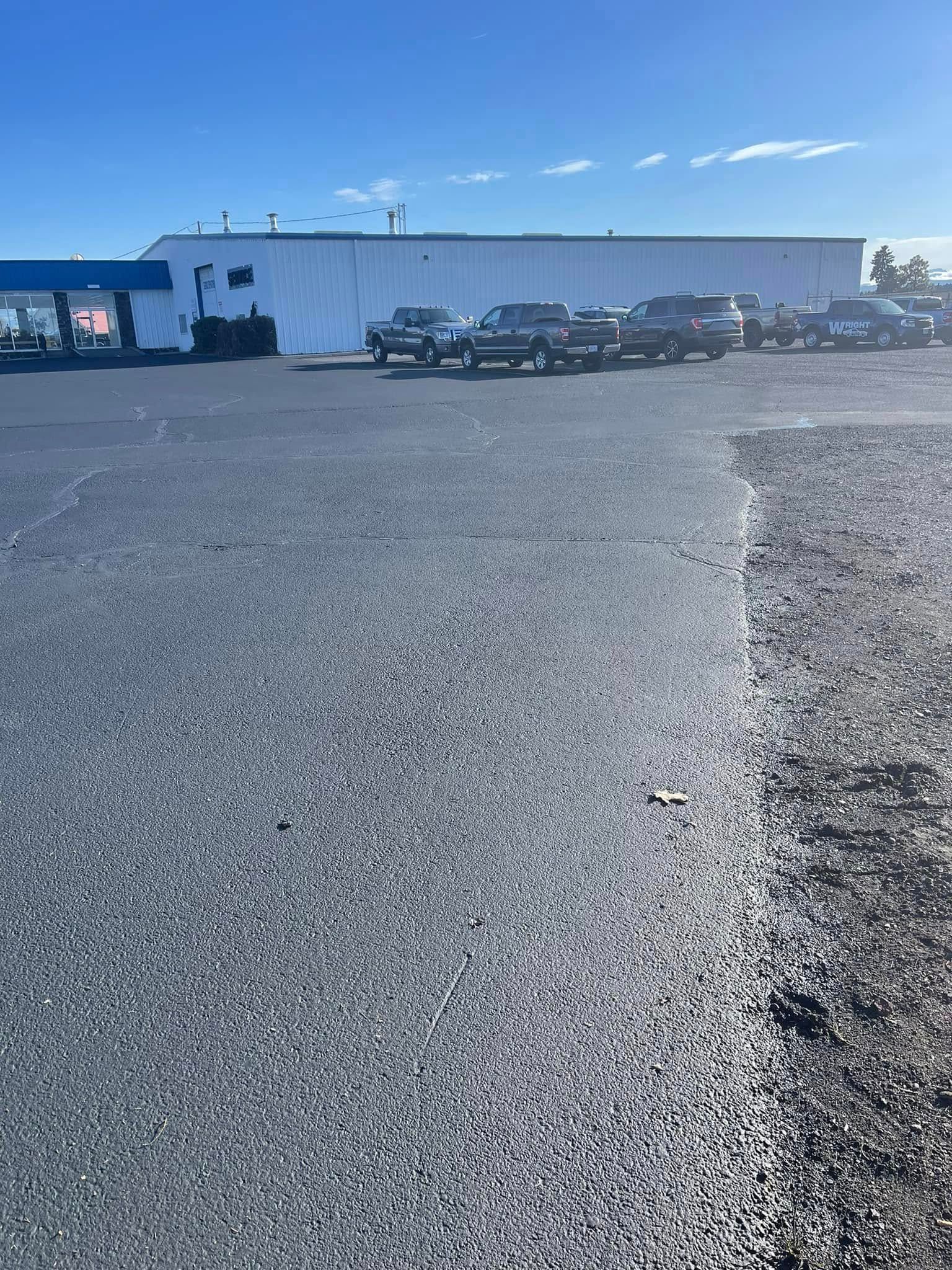 A lot of cars are parked in a parking lot in front of a building.
