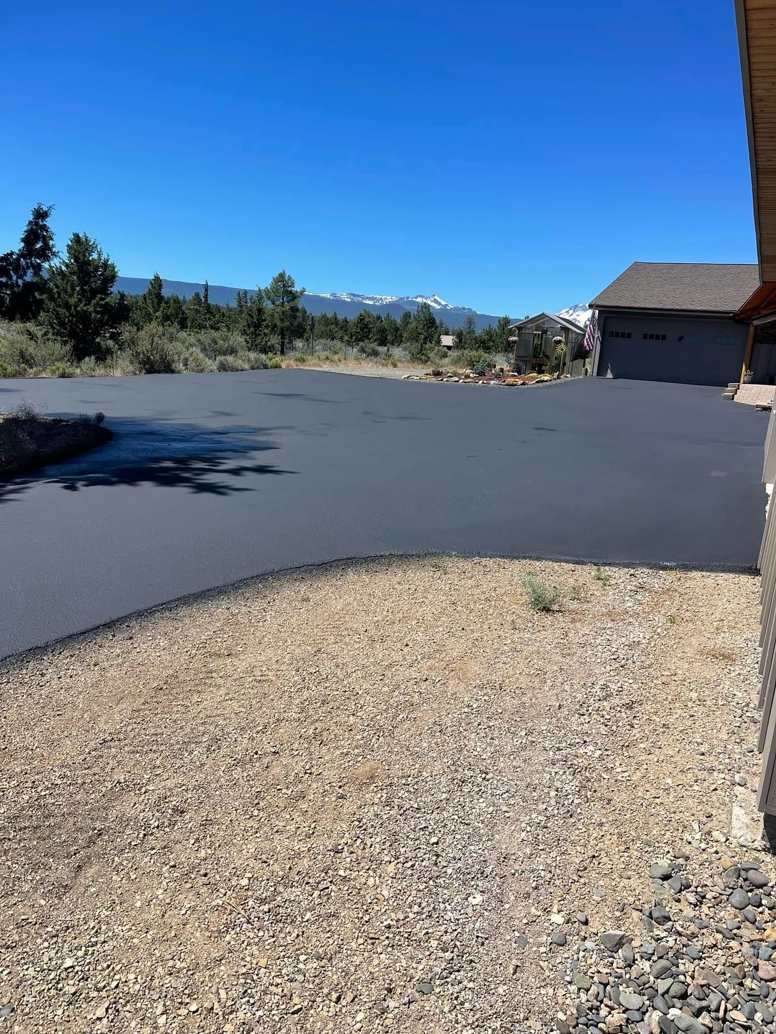 A driveway with a house in the background and mountains in the background.
