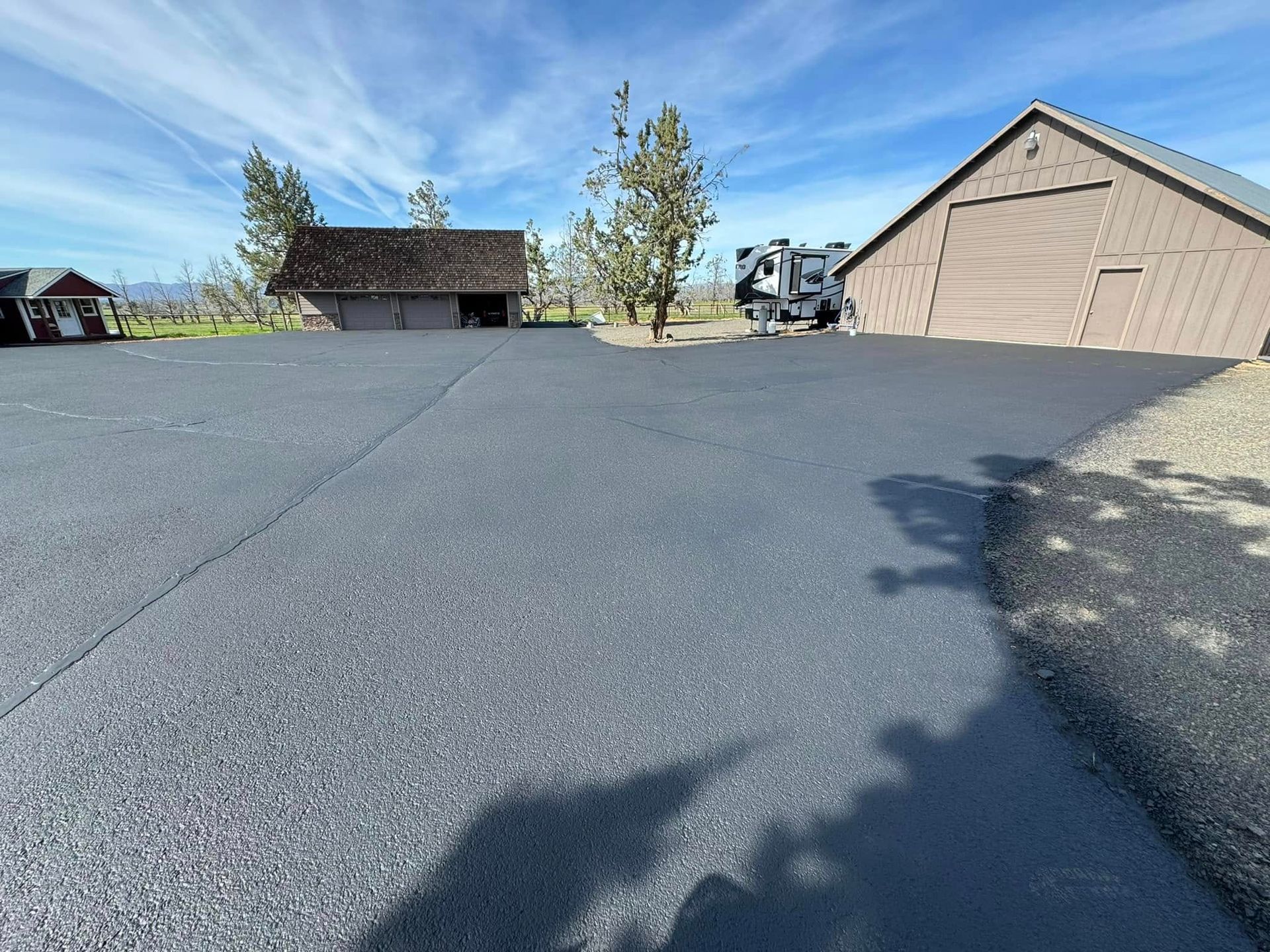 A shadow of a person is cast on the asphalt in front of a garage.