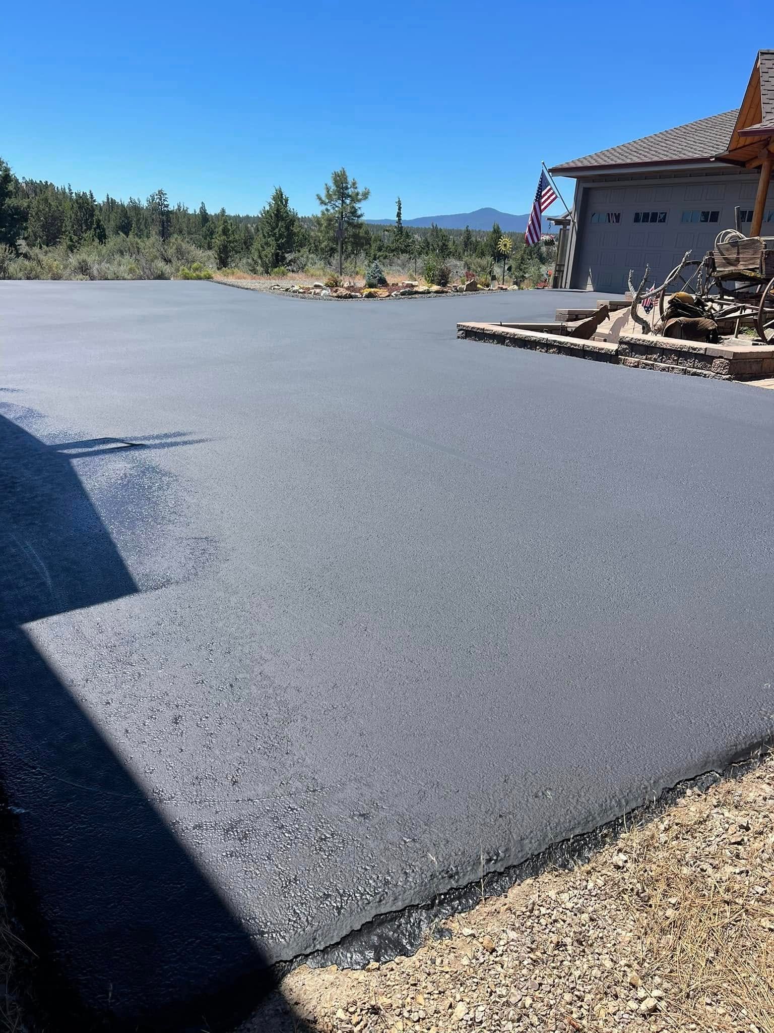 A large asphalt driveway is being built in front of a house.