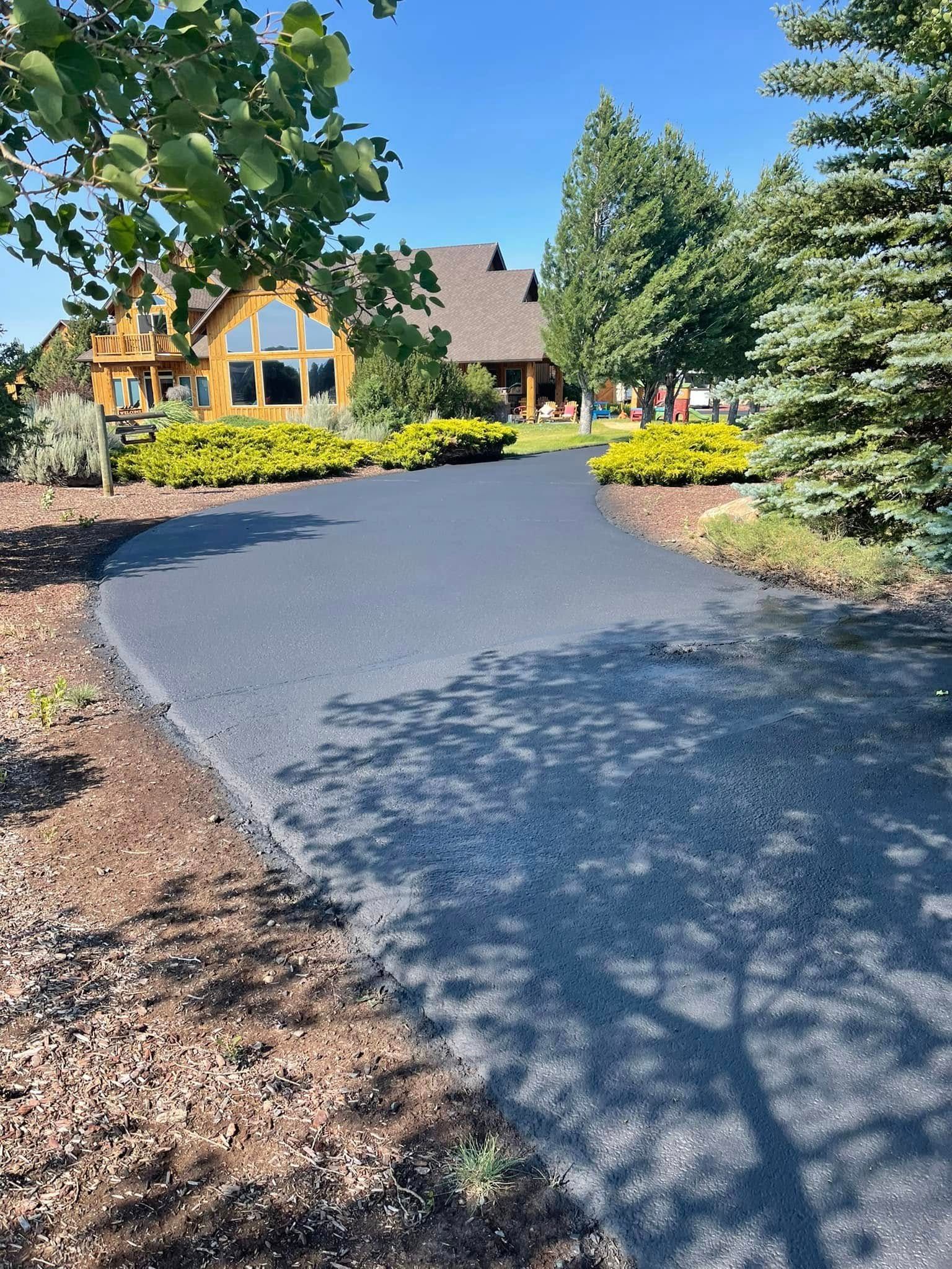 A driveway leading to a large house surrounded by trees and bushes.