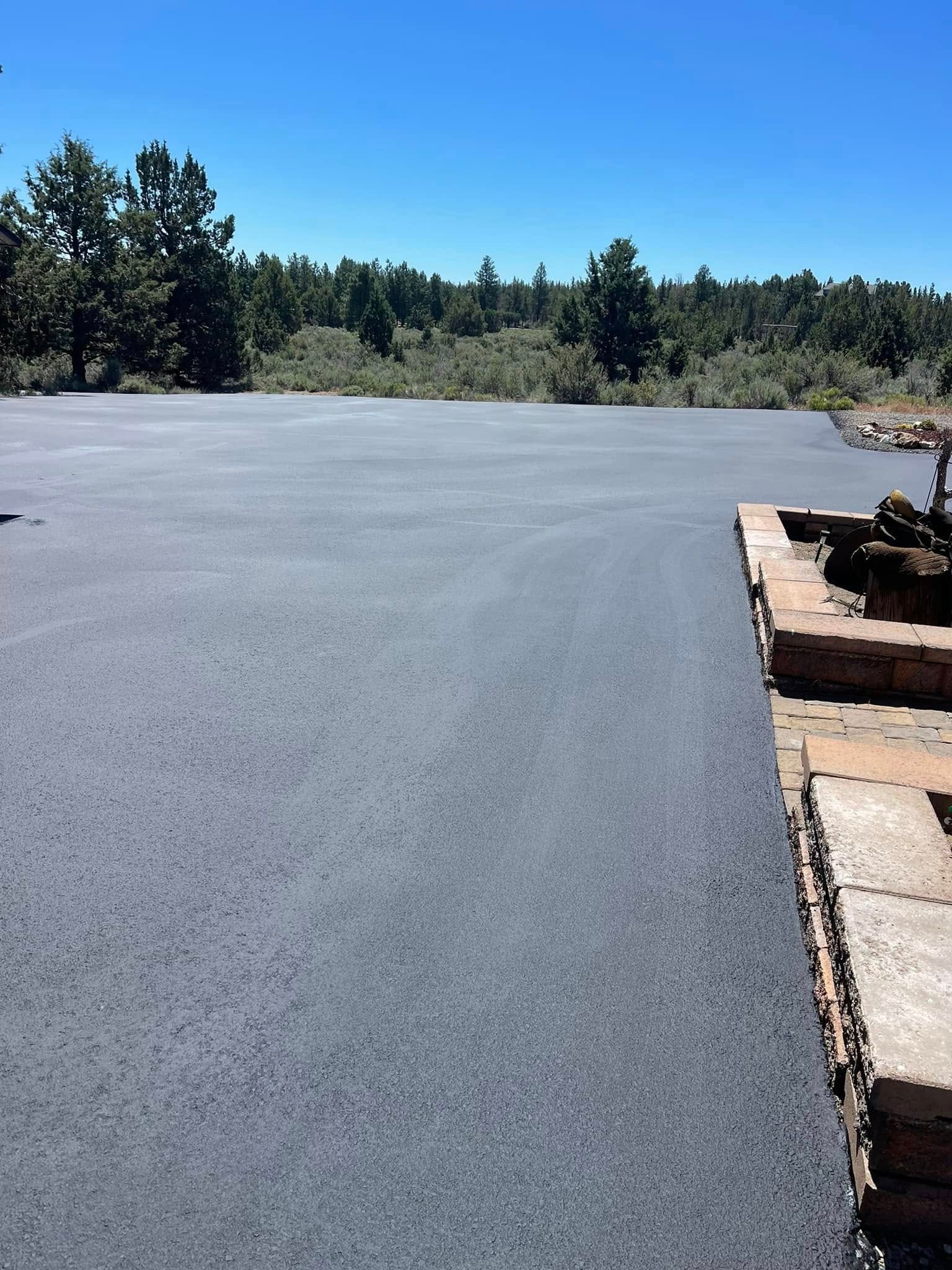 A large empty parking lot with trees in the background on a sunny day.