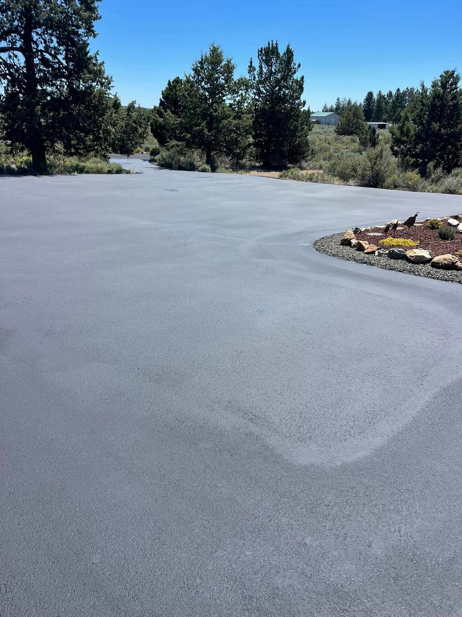 A gray asphalt road with trees in the background