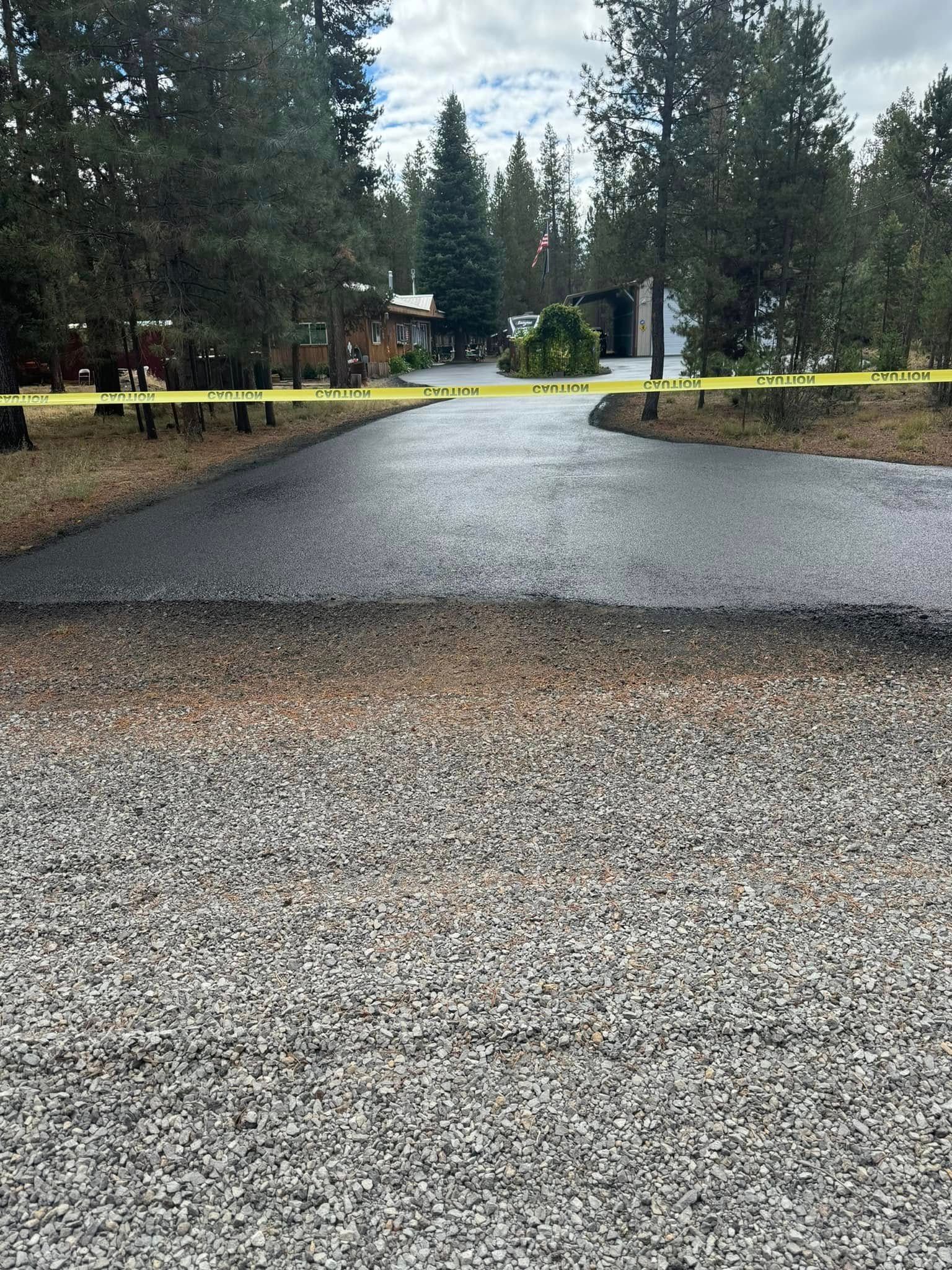 A newly paved driveway with a yellow tape surrounding it.