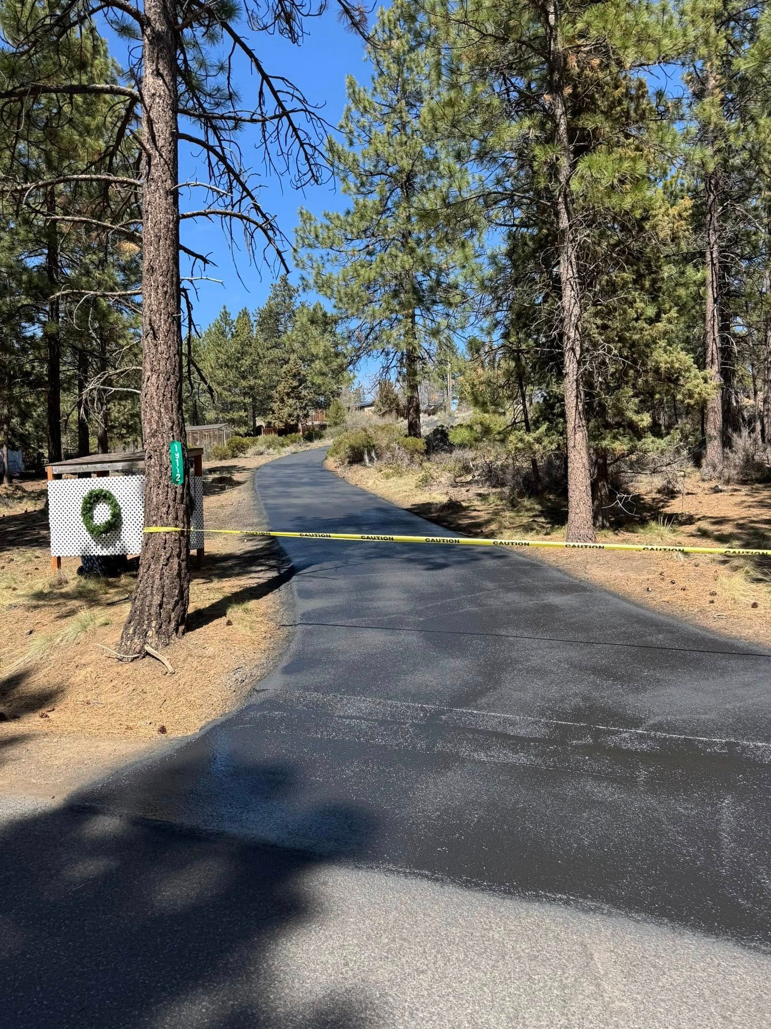 A road with a wreath on the side of it surrounded by trees.