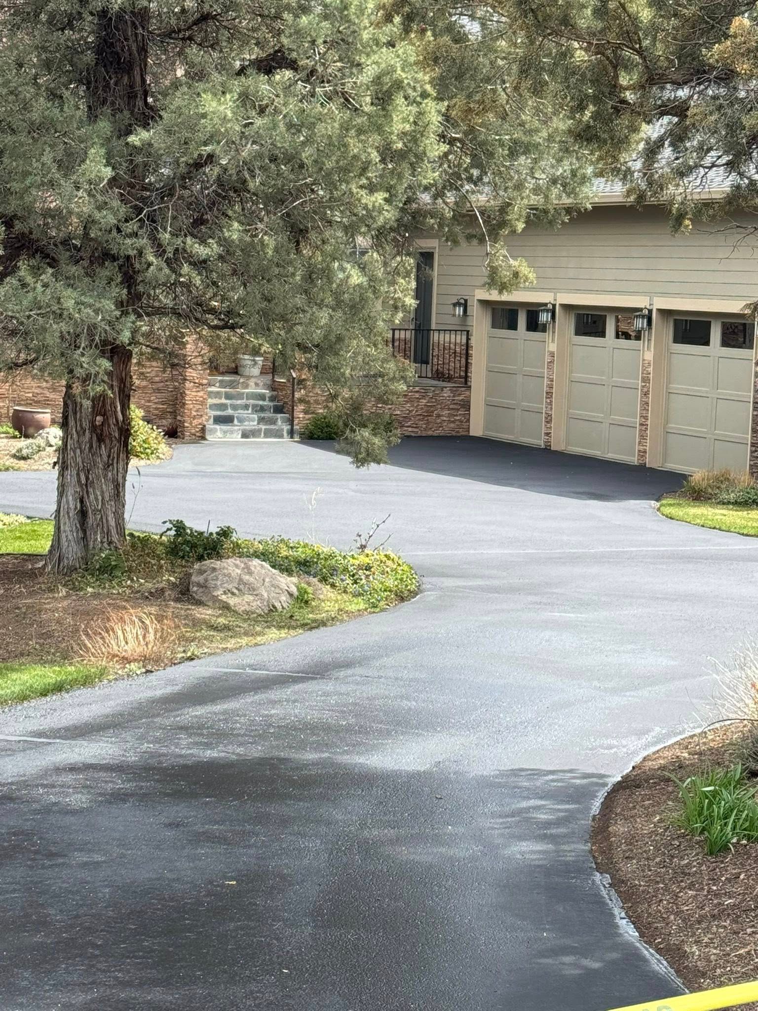 A driveway leading to a house with three garage doors.