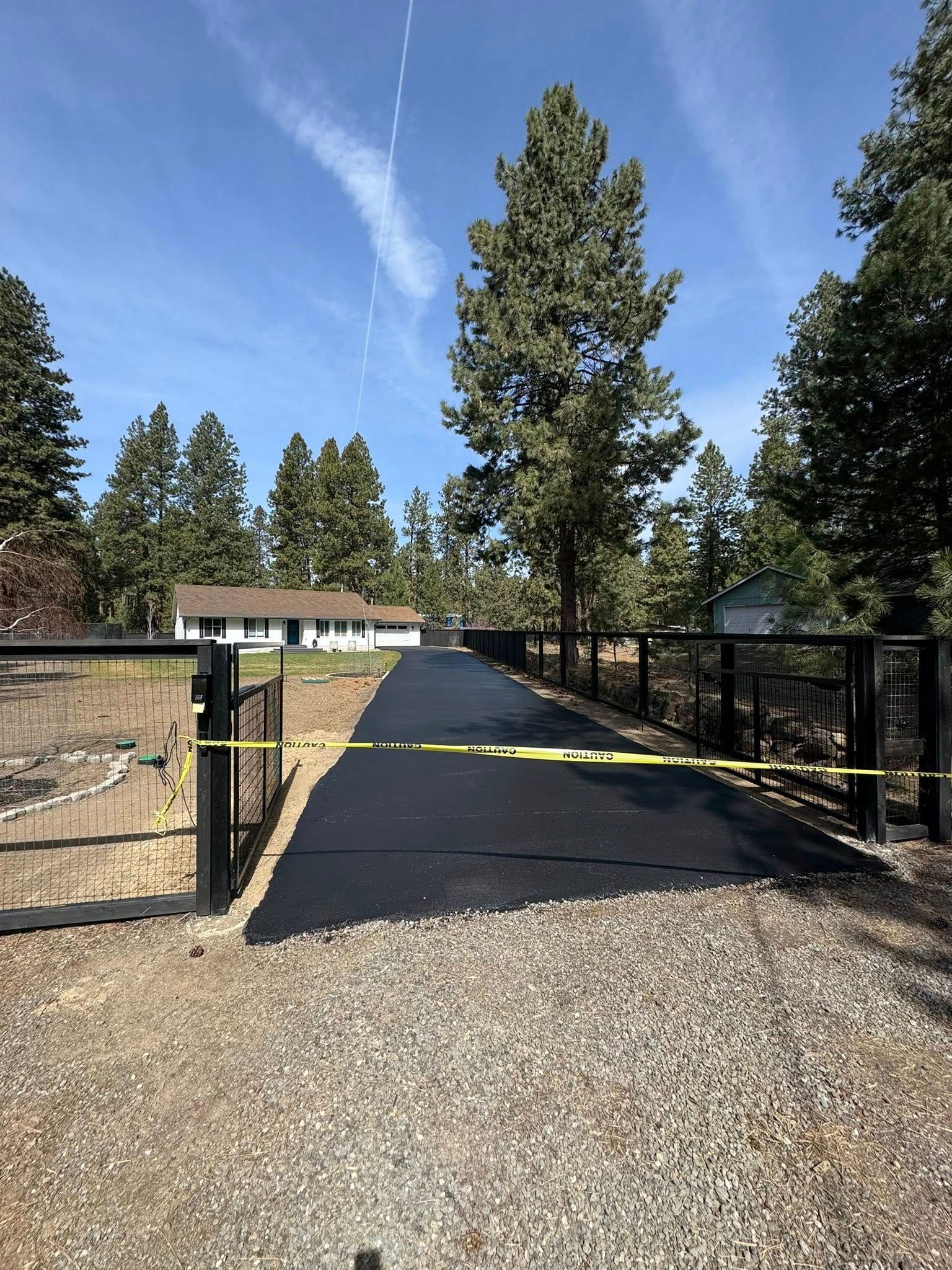 A driveway with a fence and a house in the background.