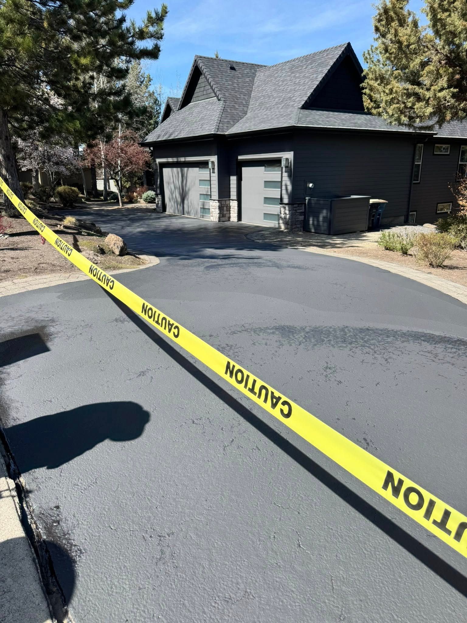 A caution tape is covering a driveway in front of a house.