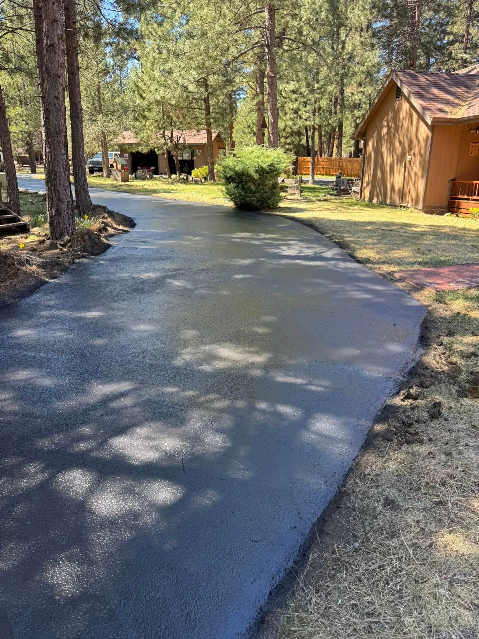 A newly paved driveway leading to a house in the woods.