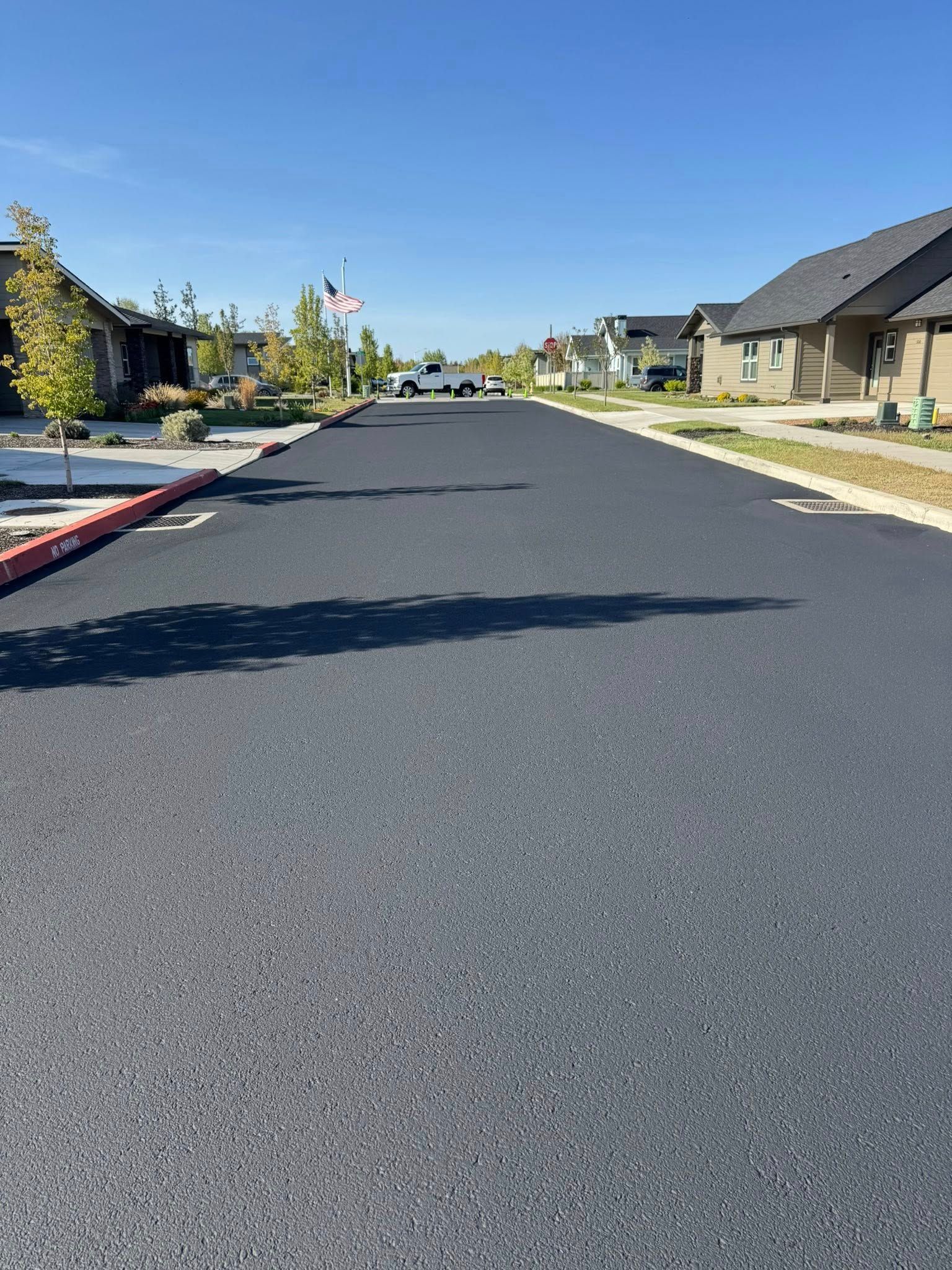 A residential street with a lot of cars parked on the side of it.