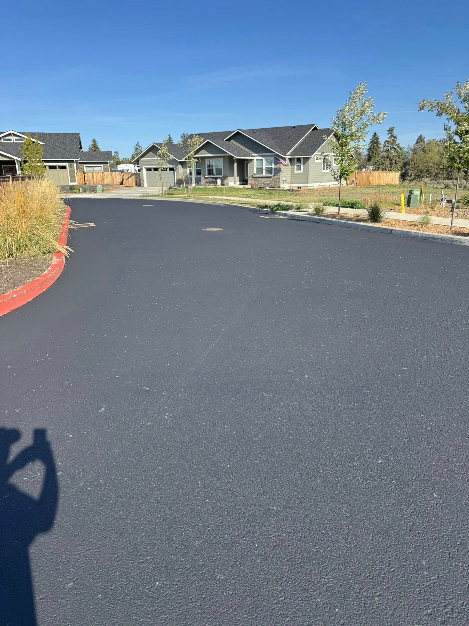 A person is taking a picture of a road with houses in the background.