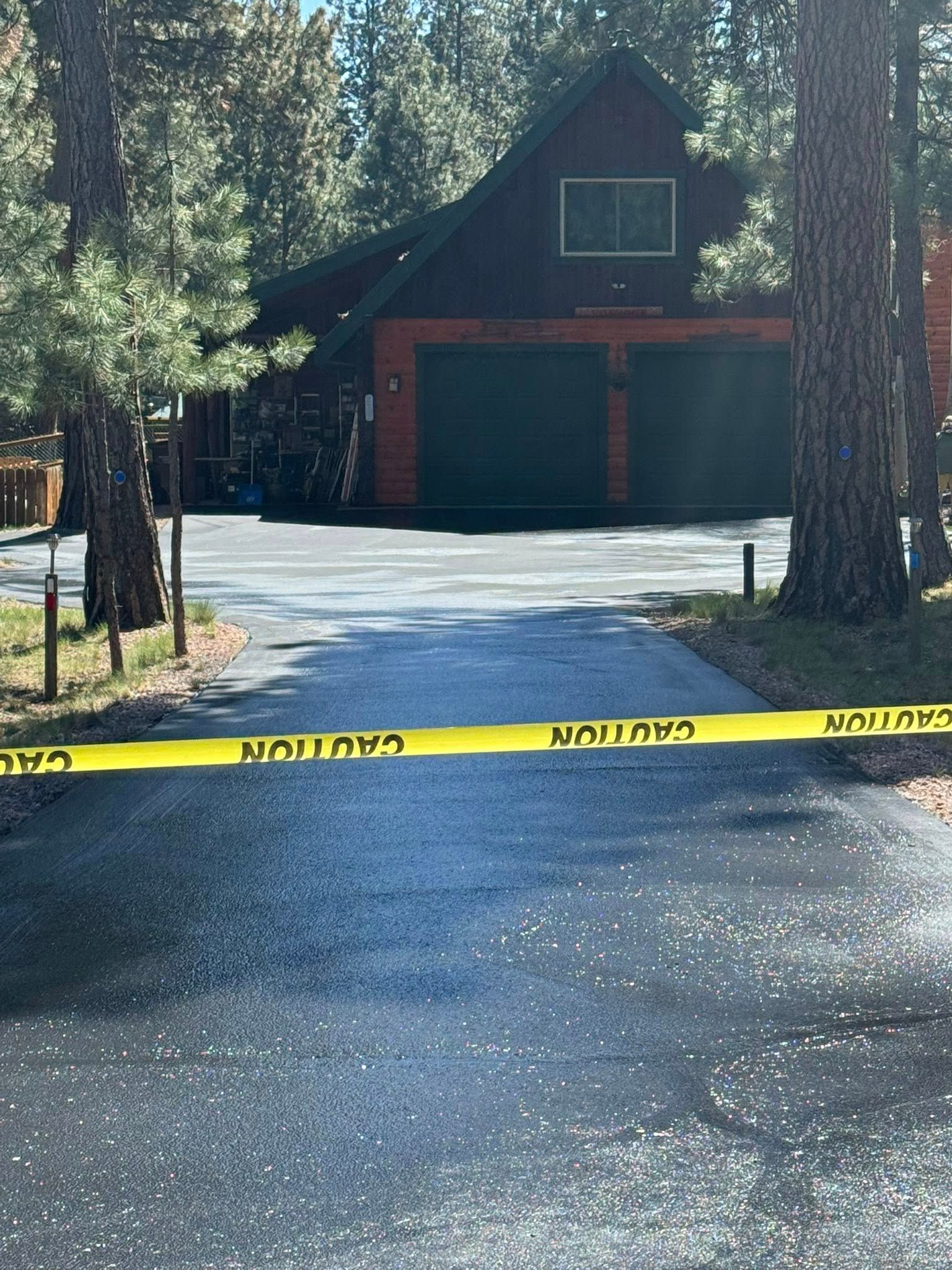 A yellow caution tape is on the side of a road in front of a house.