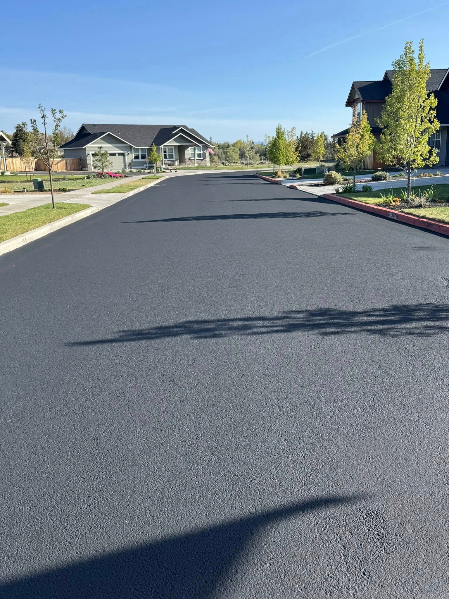 A black asphalt road in a residential area with houses on both sides.