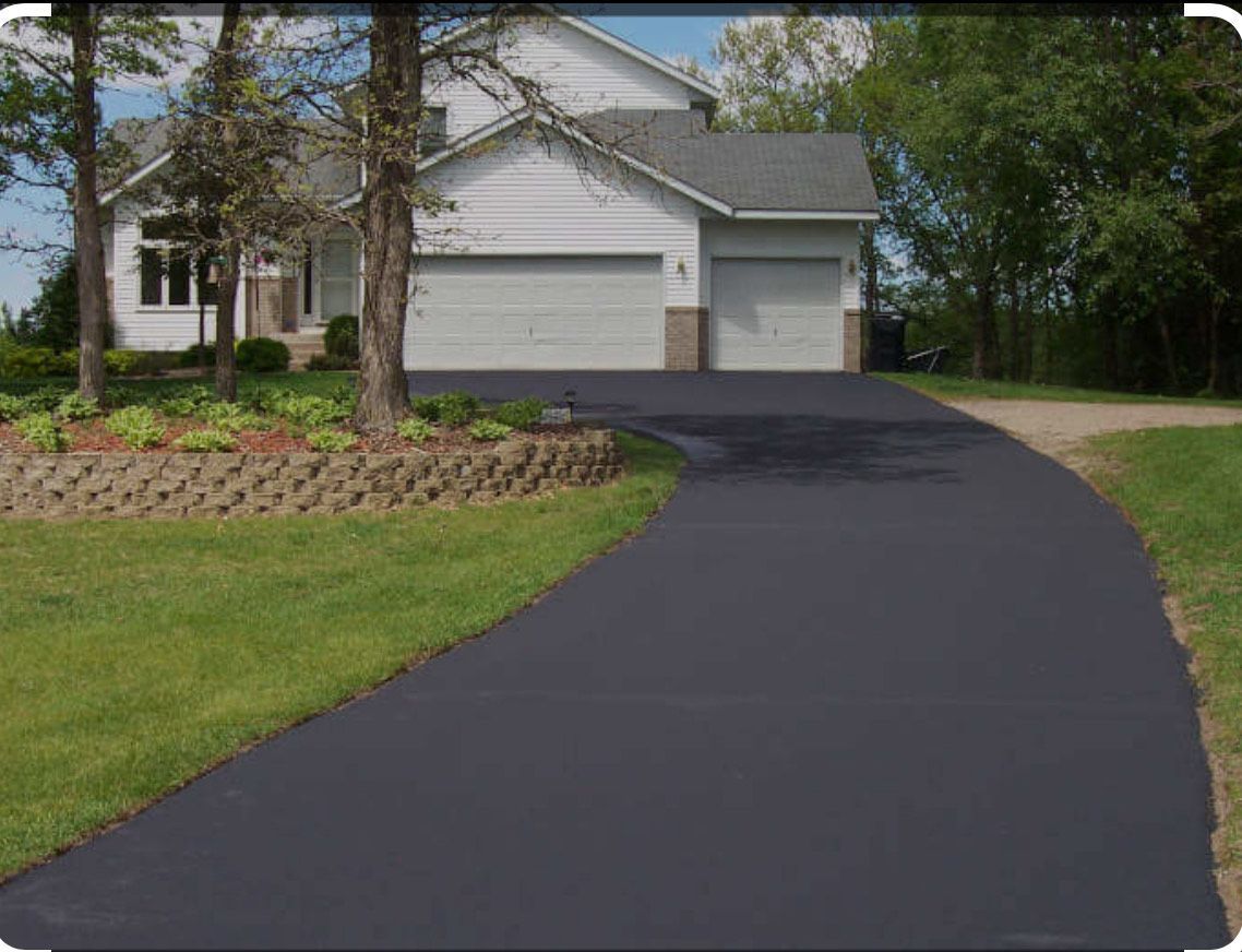 A white house with a black driveway leading to it