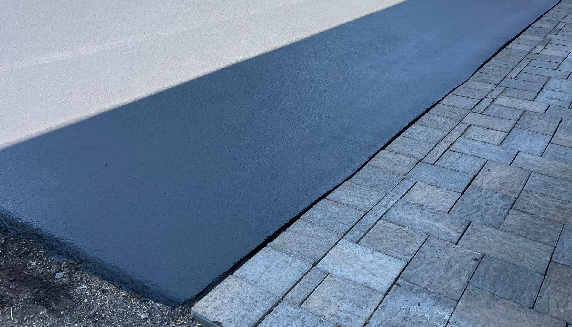 A close up of a brick sidewalk with a concrete curb.