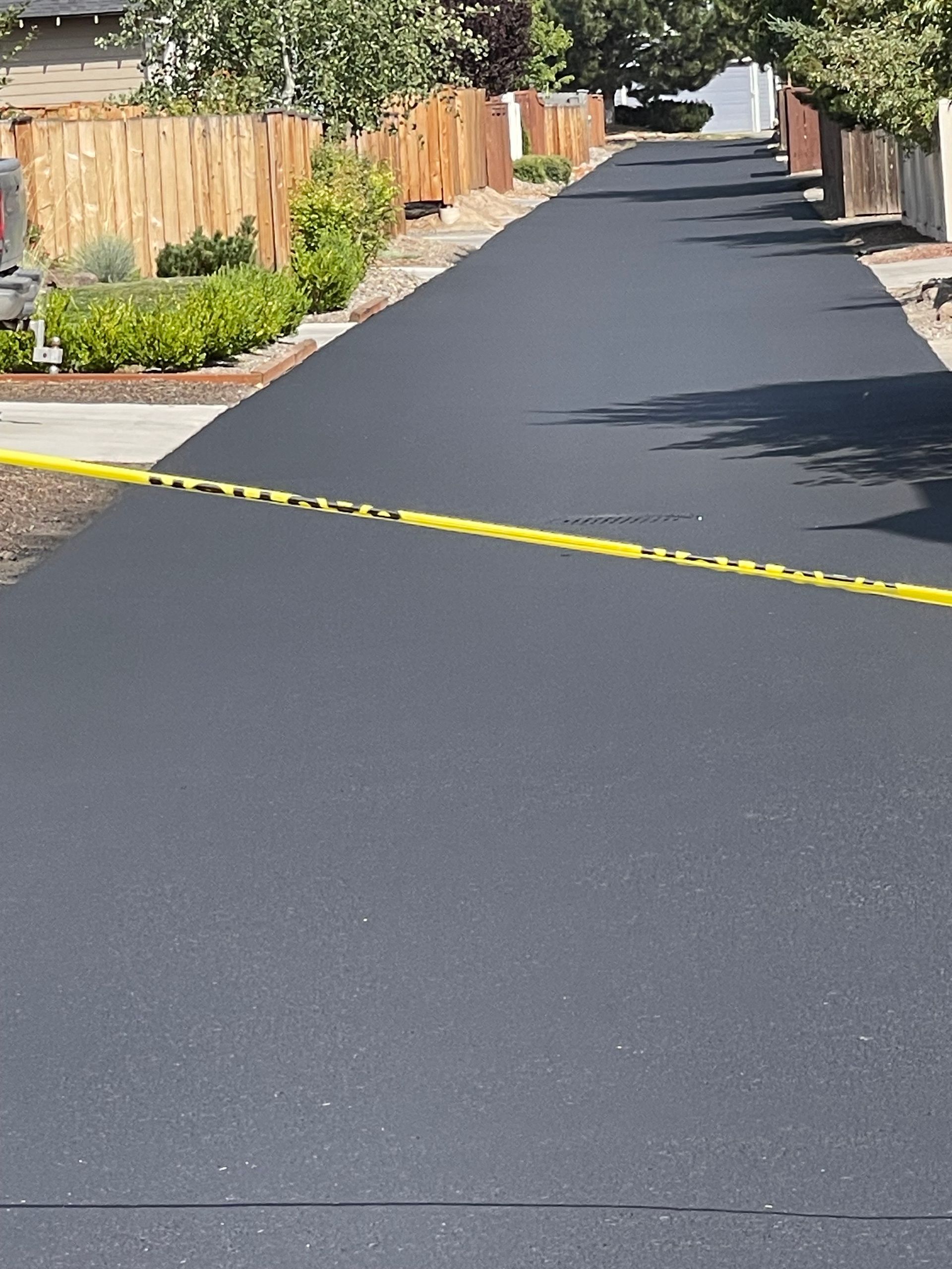 A black road with a yellow tape on the side of it