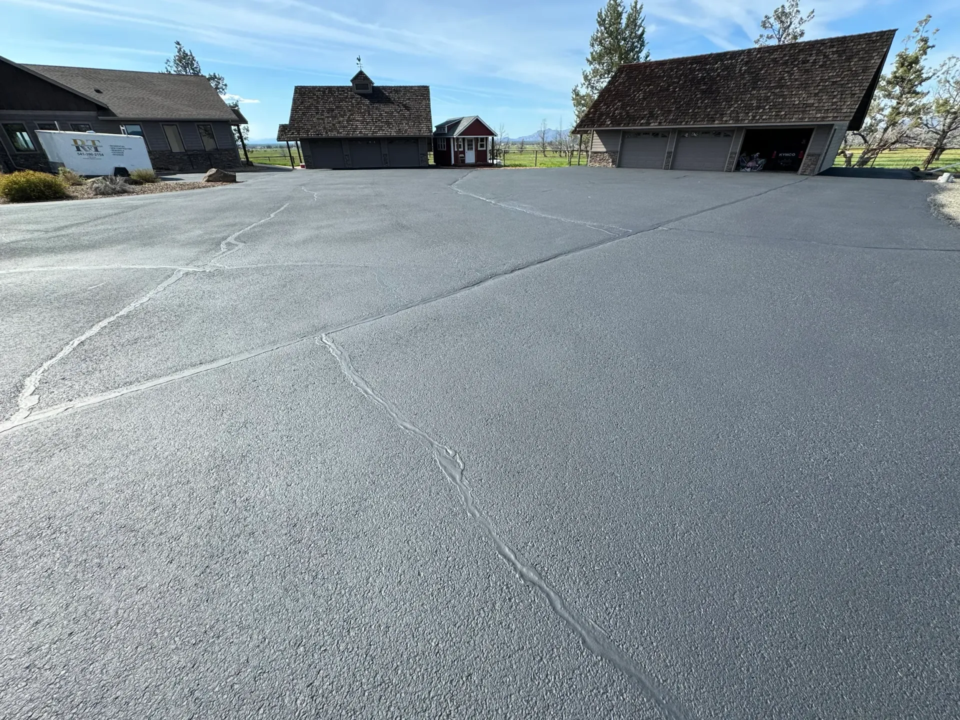 A large asphalt driveway with a house in the background.