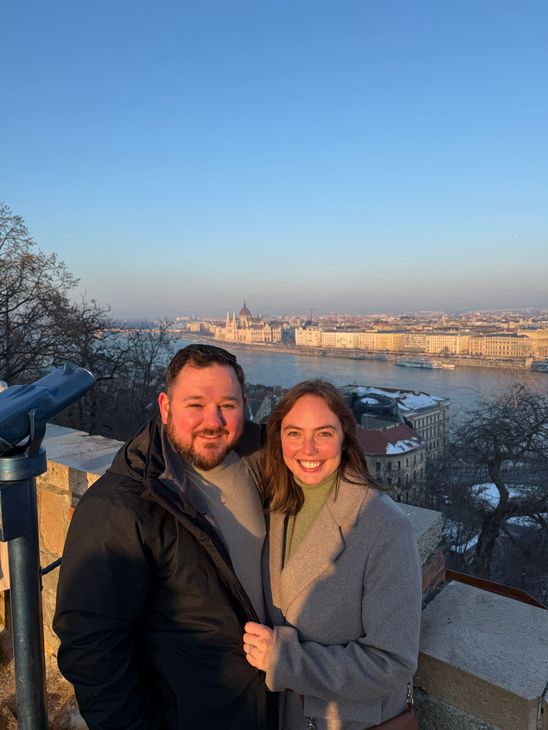 travel agent and husband in budapest with the danube river and parliament in the background
