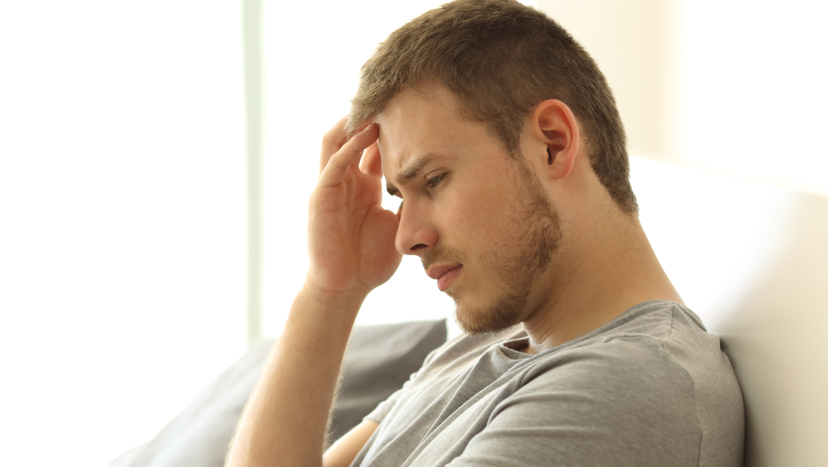 a man sitting on a couch with his hand on his head