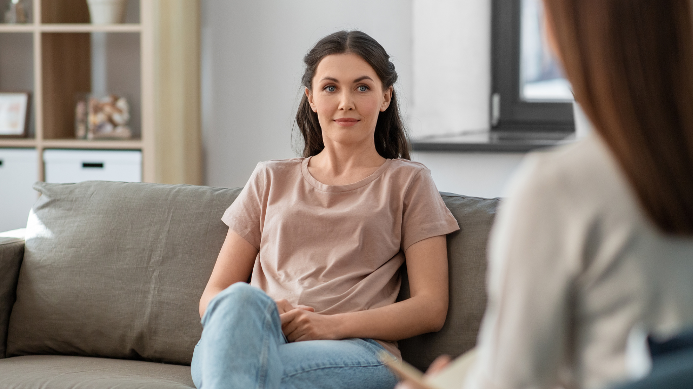 a woman sits on a couch holding her hands together