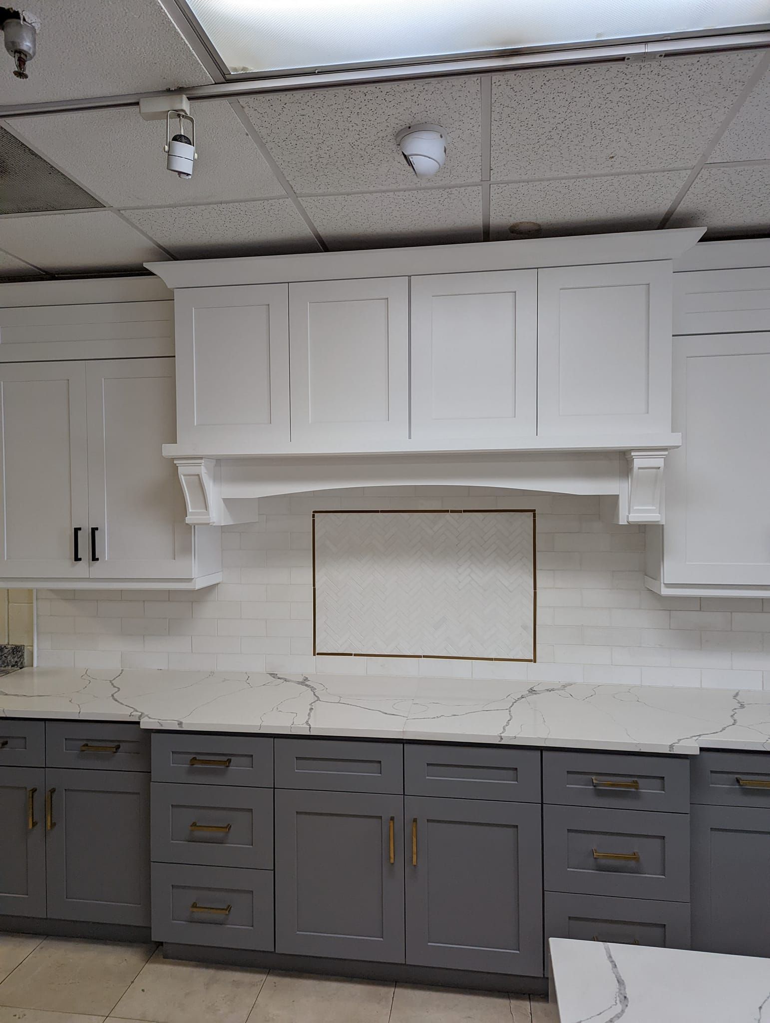 Kitchen cabinets: white uppers, gray lowers, white backsplash, countertop, and range hood.