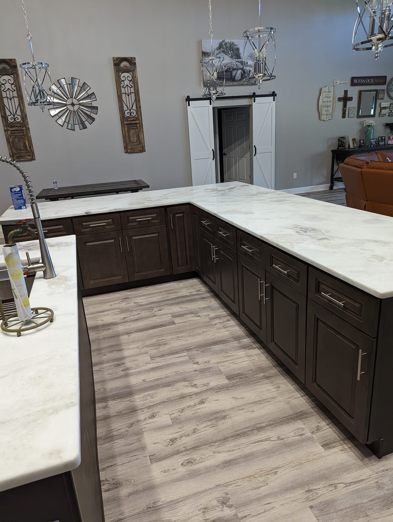 Dark brown kitchen cabinets with white countertops; light wood-look floor.