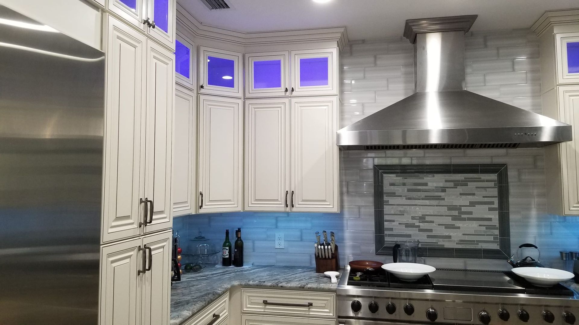 Kitchen with white cabinets, stainless steel appliances, and blue accent lighting.