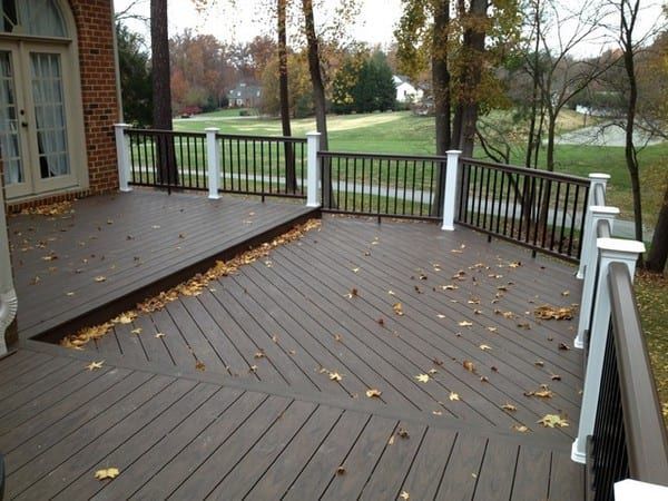 A large deck with a railing and leaves on it