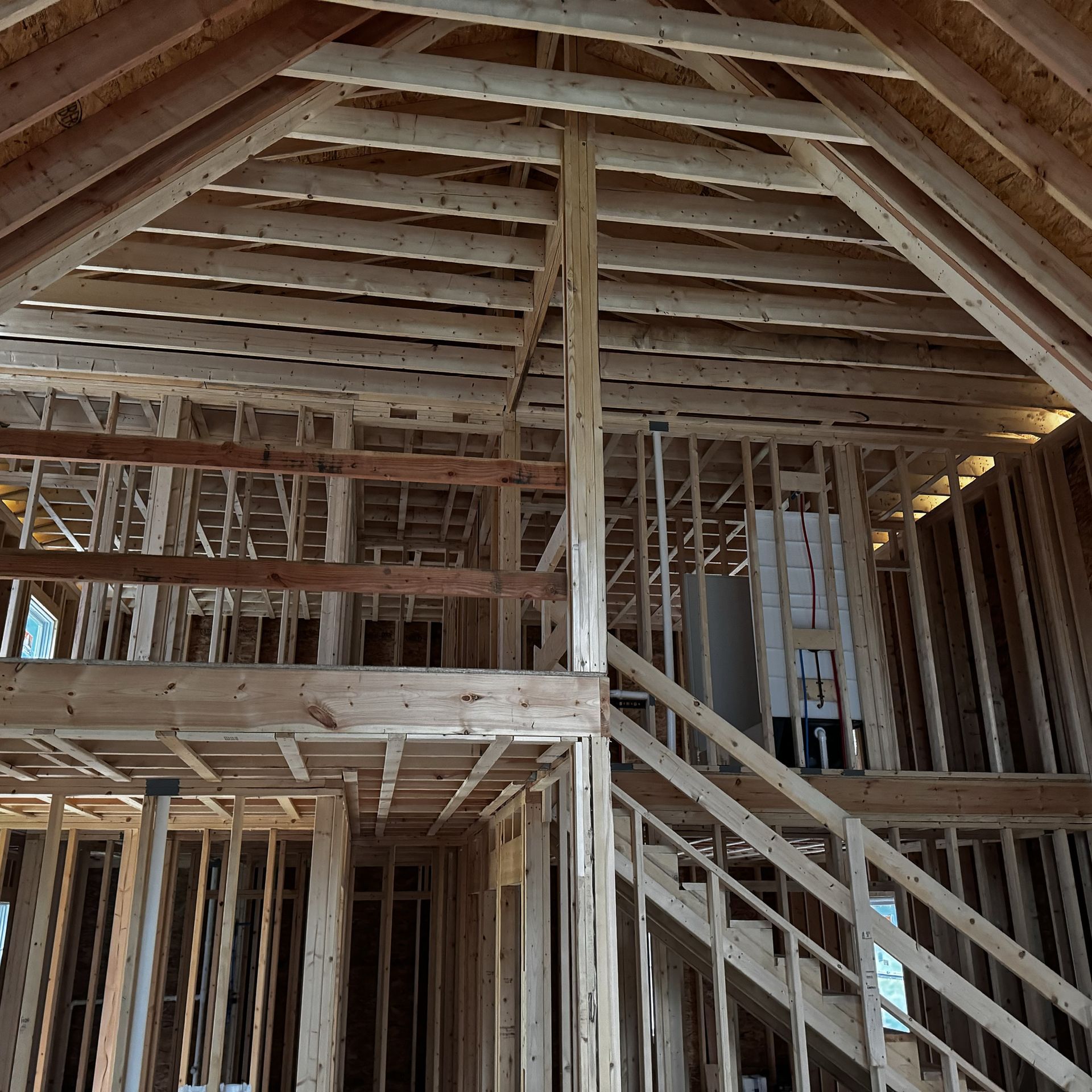 The inside of a house under construction with wooden beams and stairs