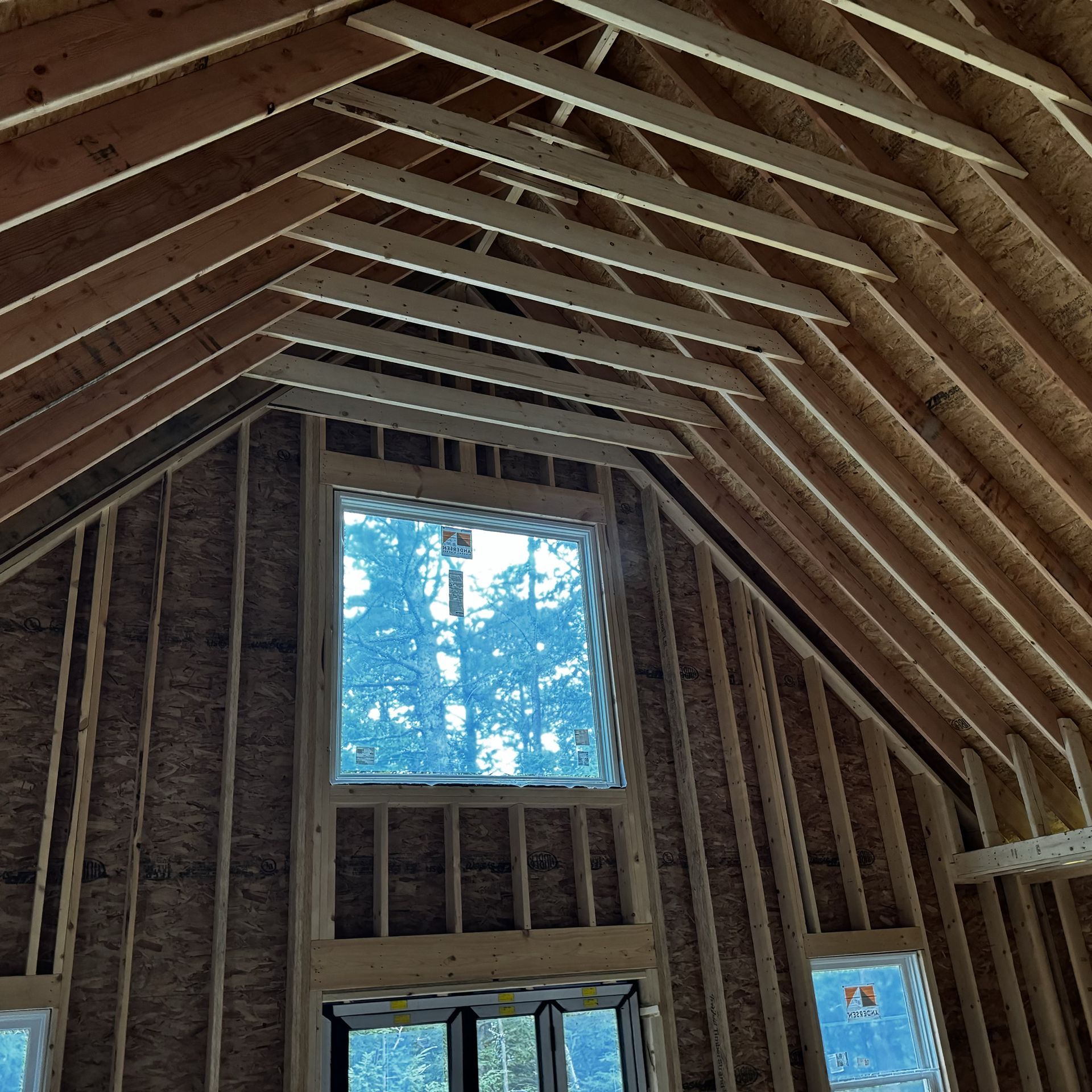 The inside of a house under construction with a vaulted ceiling and lots of windows