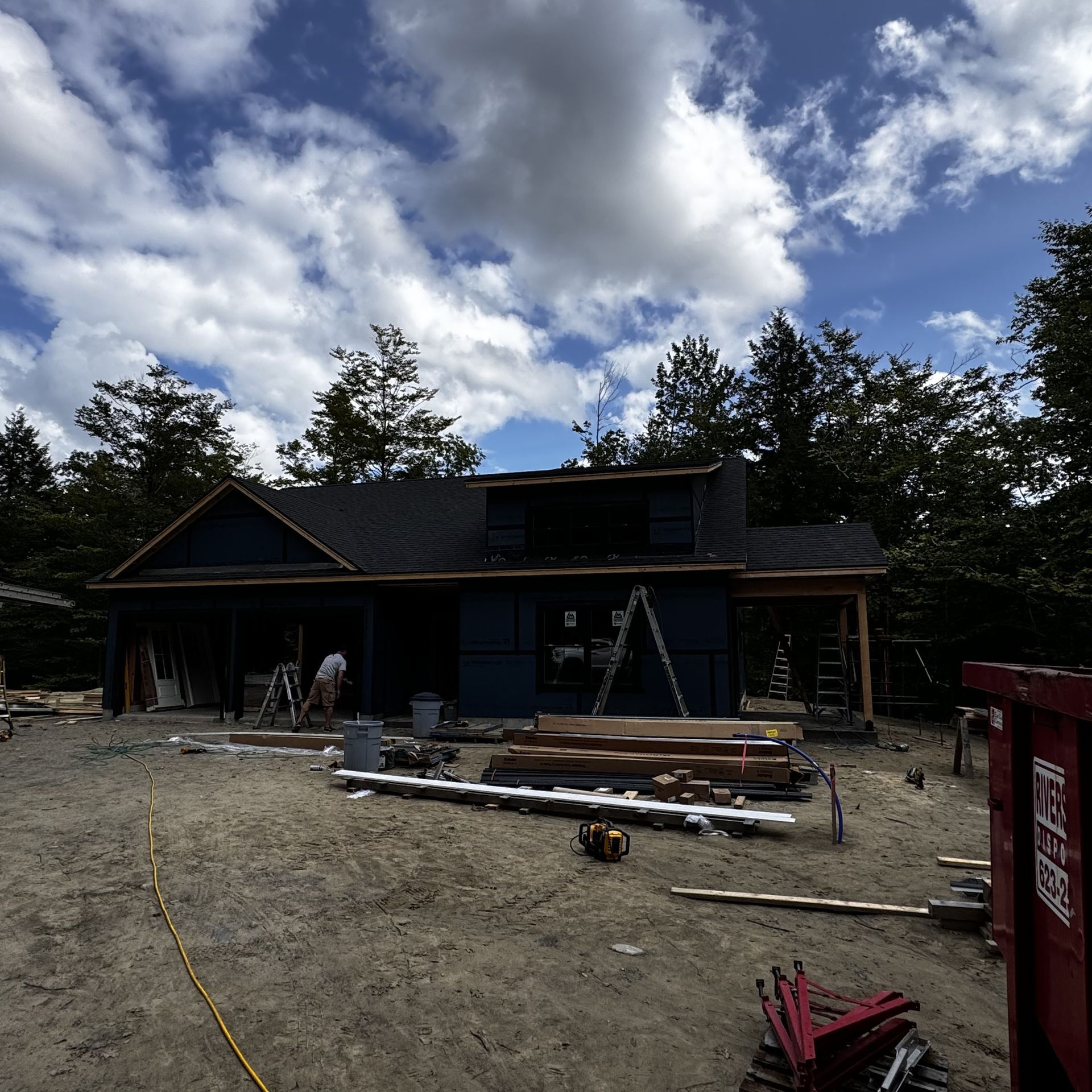 A house under construction with a red dumpster in front of it