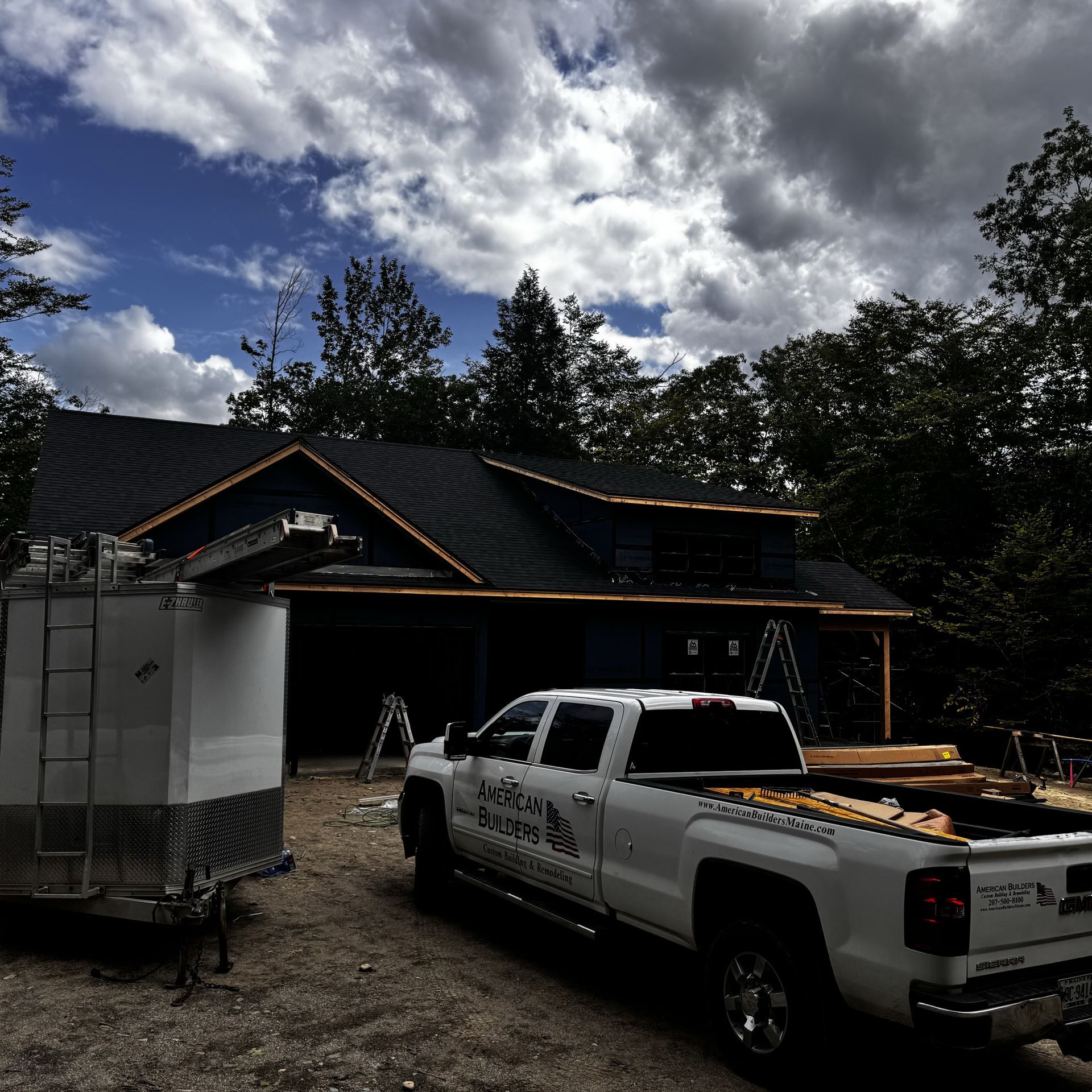 A white truck is parked in front of a house under construction