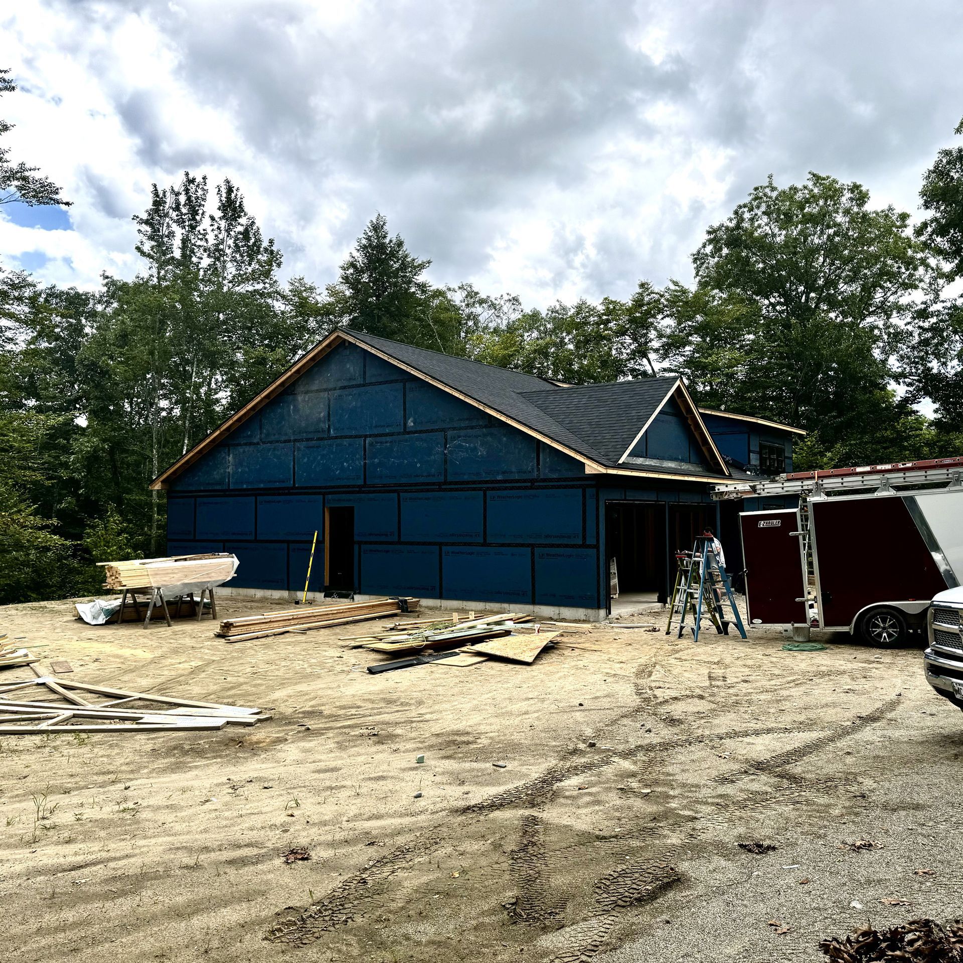 A blue house is being built in the middle of a dirt field