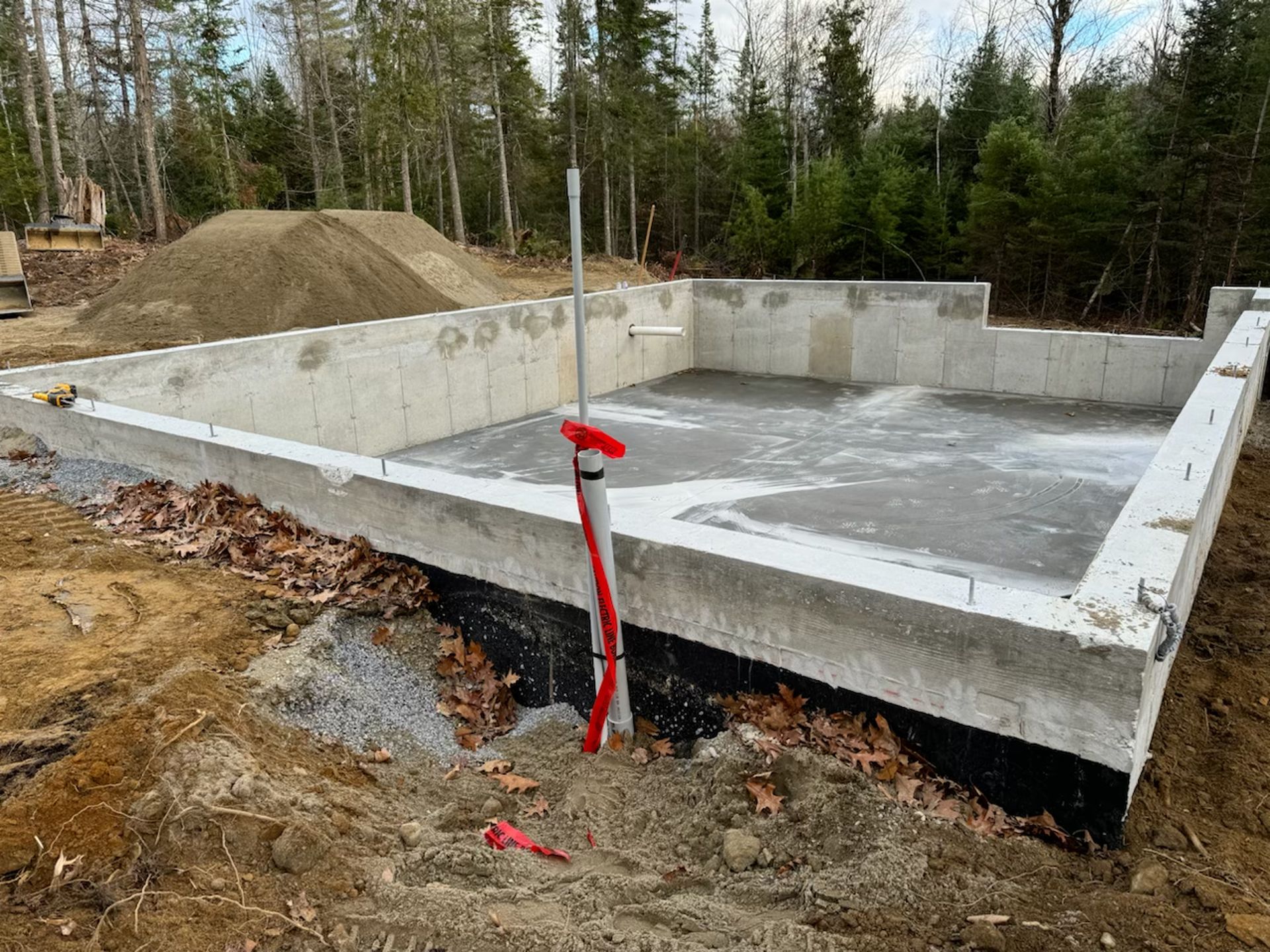 A concrete foundation for a house is being built in the woods.