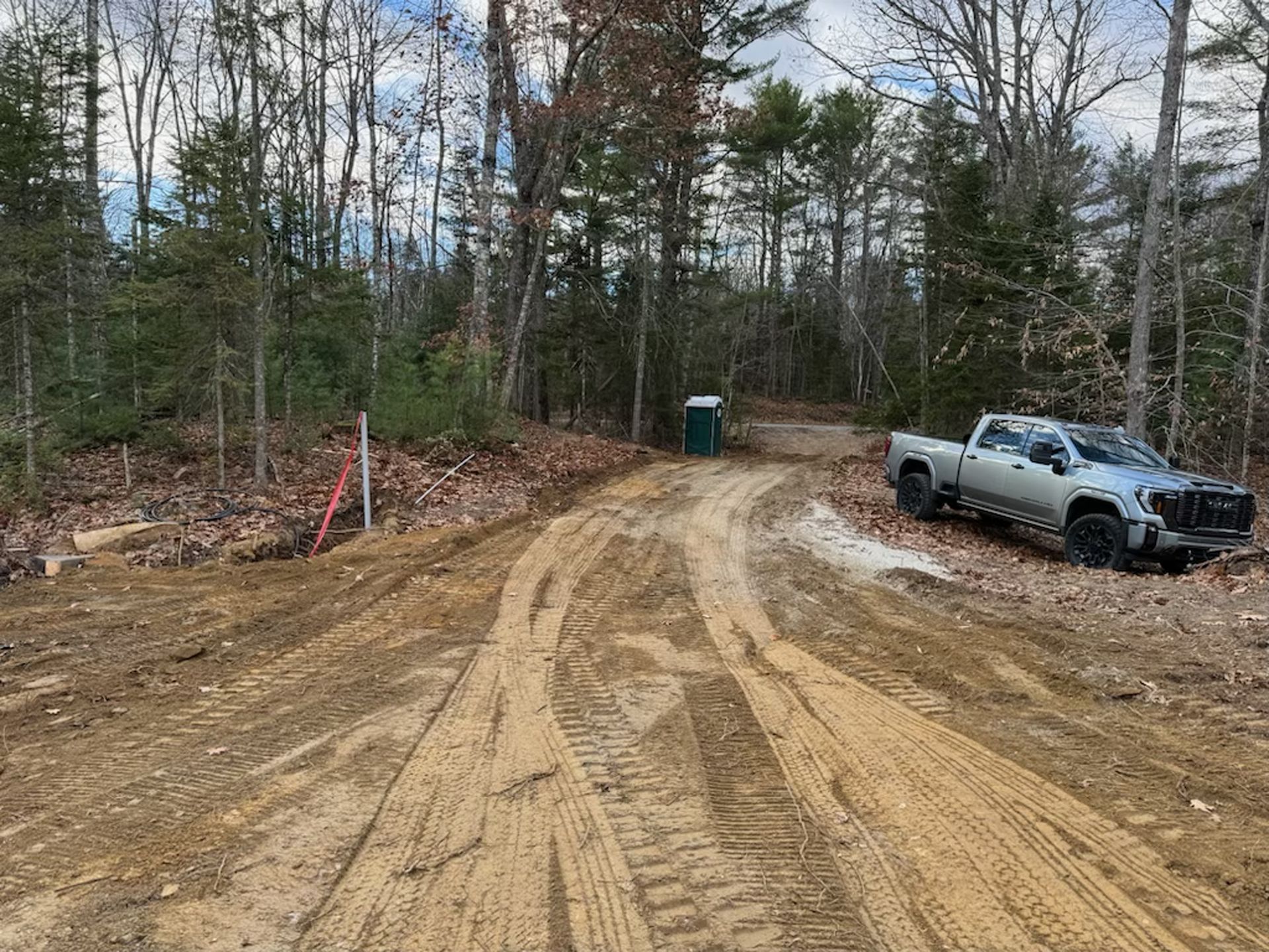 A truck is parked on the side of a dirt road.