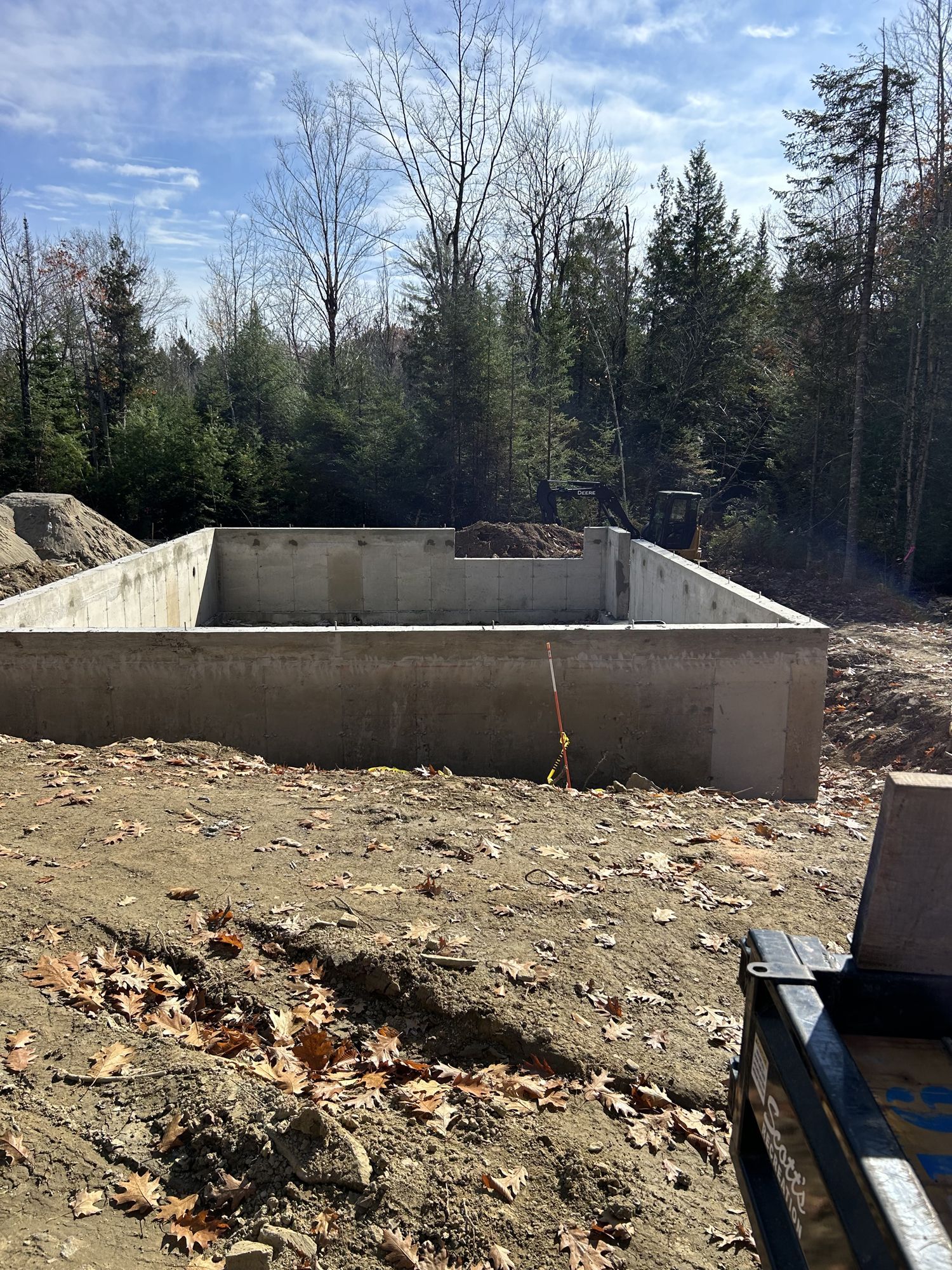 A large concrete foundation is being built in the middle of a dirt field.