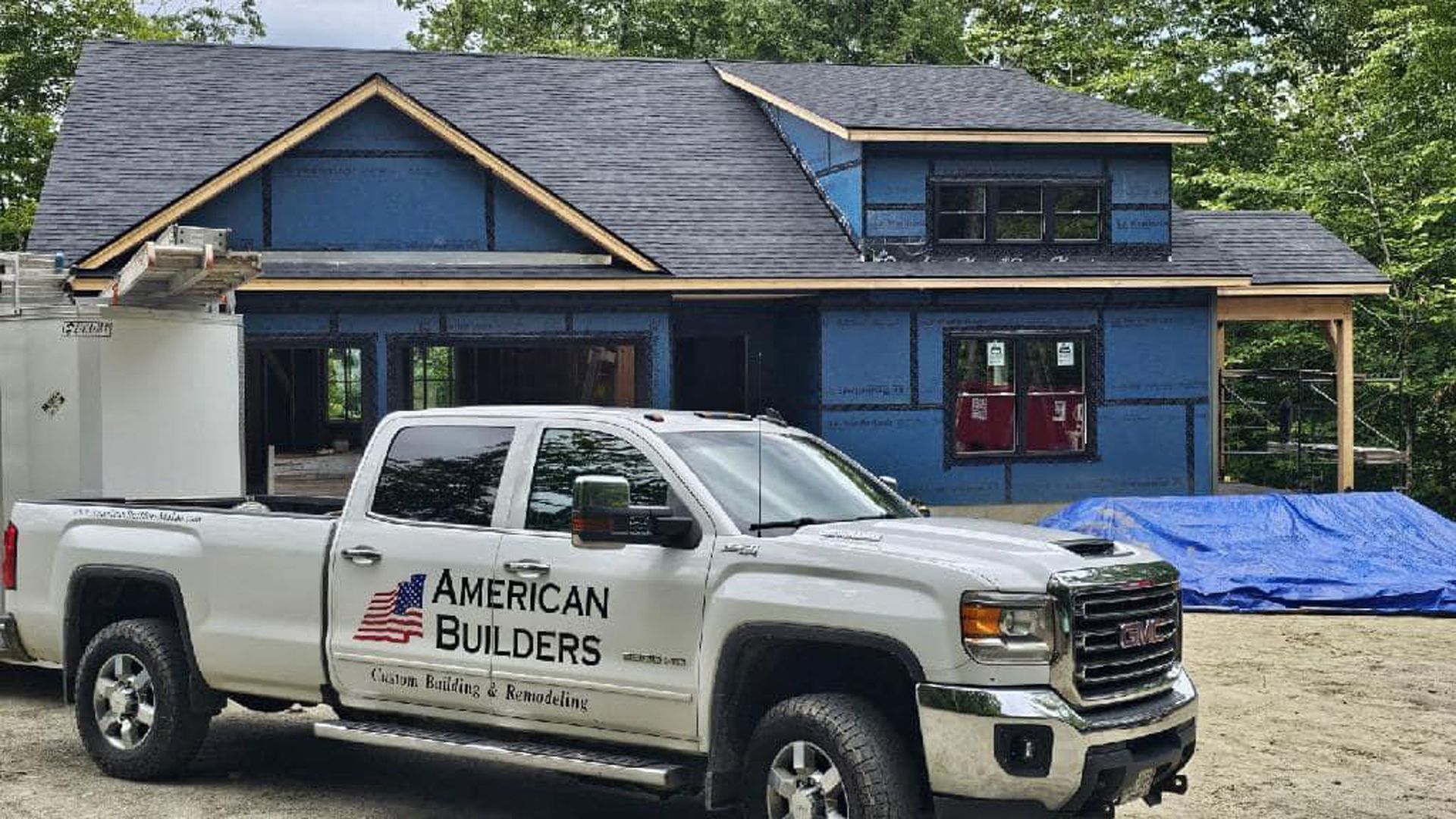 A white truck is parked in front of a house under construction.