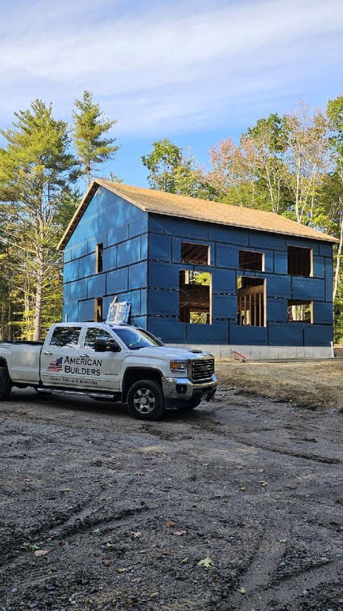 A white truck is parked in front of a house under construction.