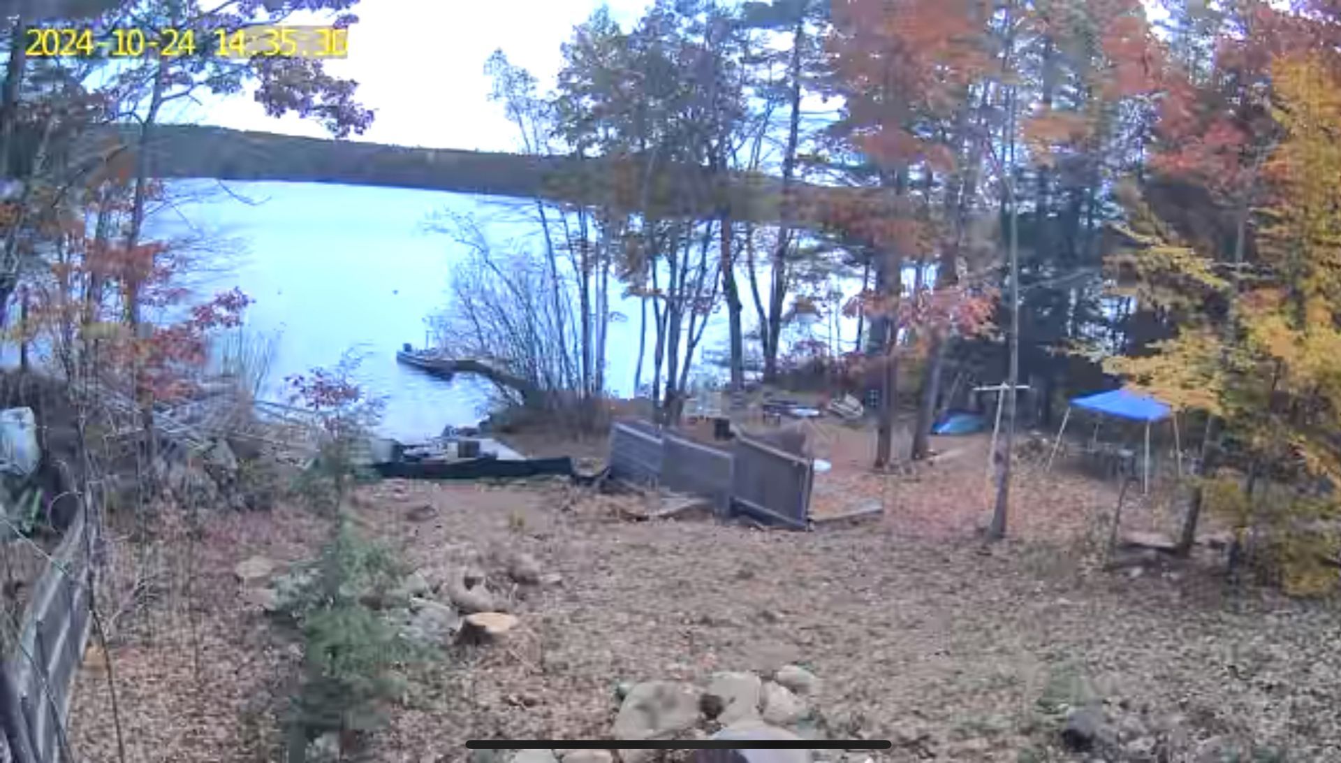 A camera is taking a picture of a lake surrounded by trees.