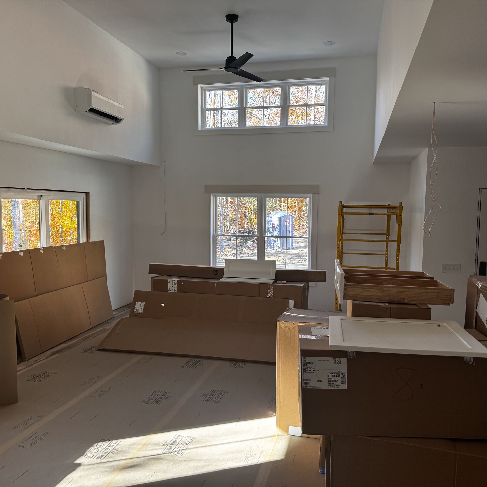 A room with a lot of cardboard boxes and a ceiling fan.