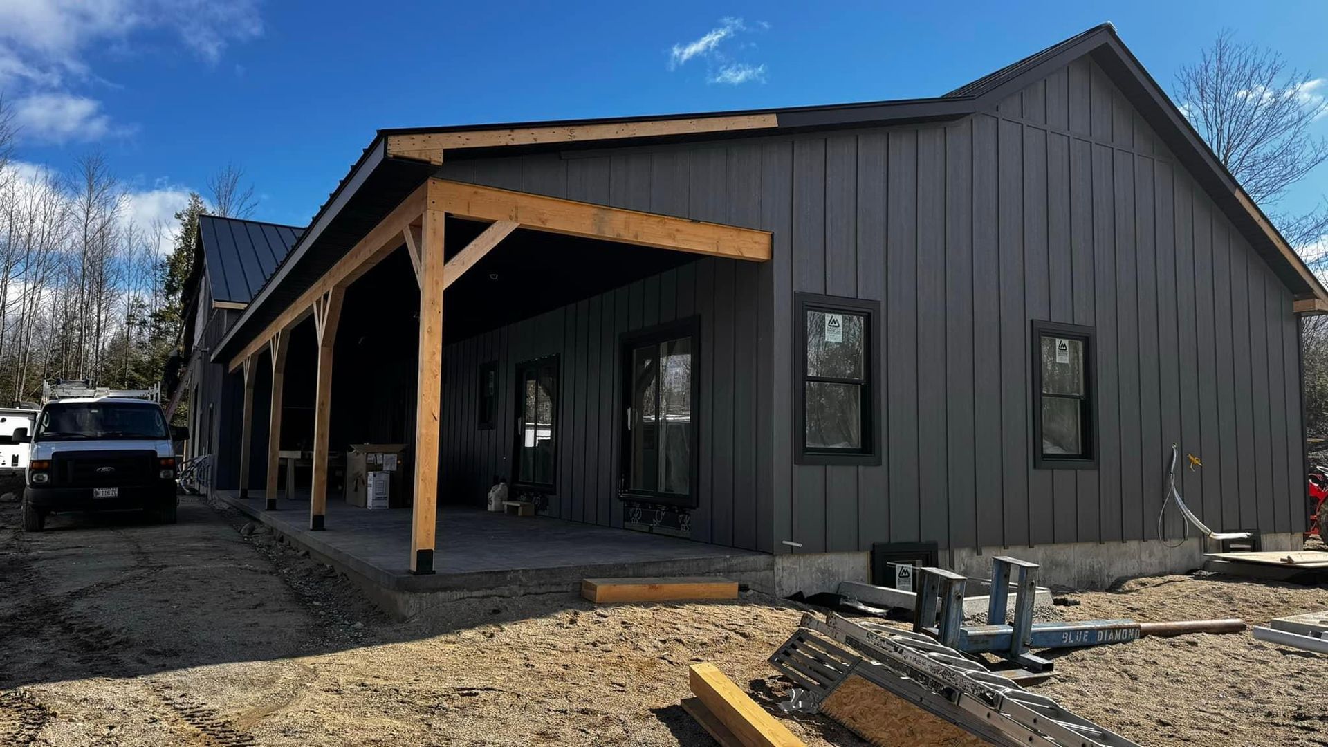 A house under construction with a porch and a truck parked in front of it.