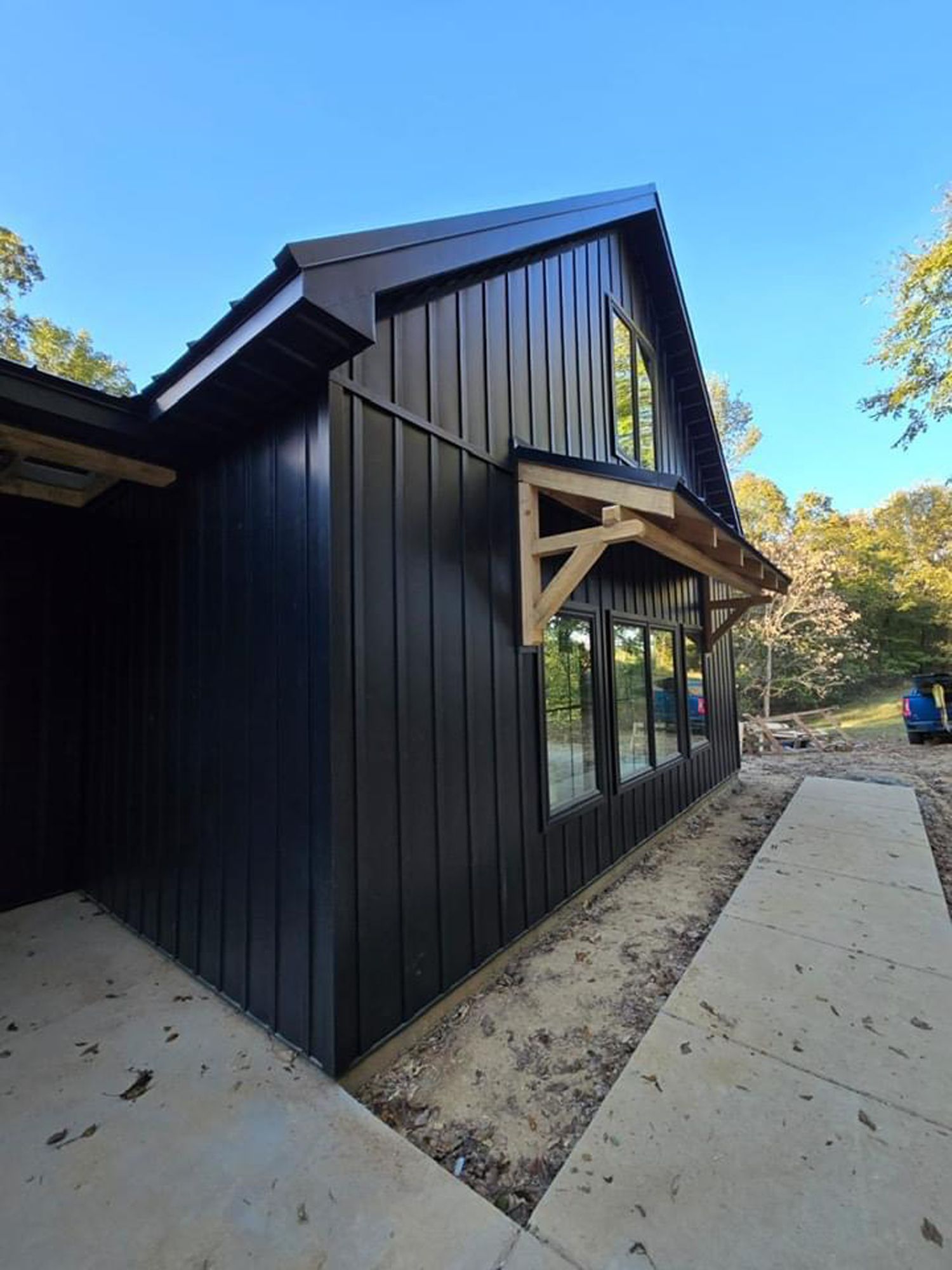 A black house with a wooden awning on the side of it.